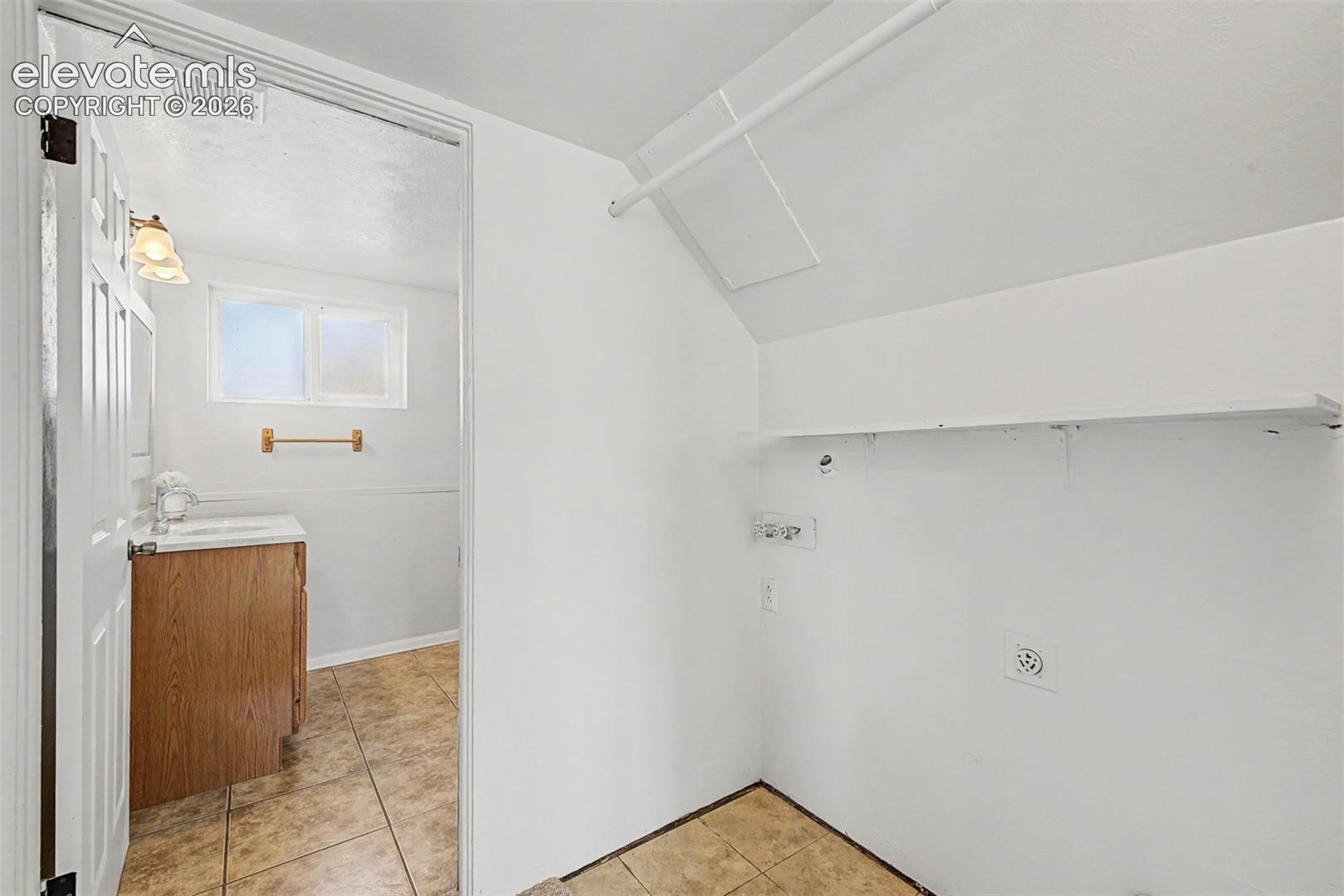 Laundry area with wall-mounted shelving and utility connections