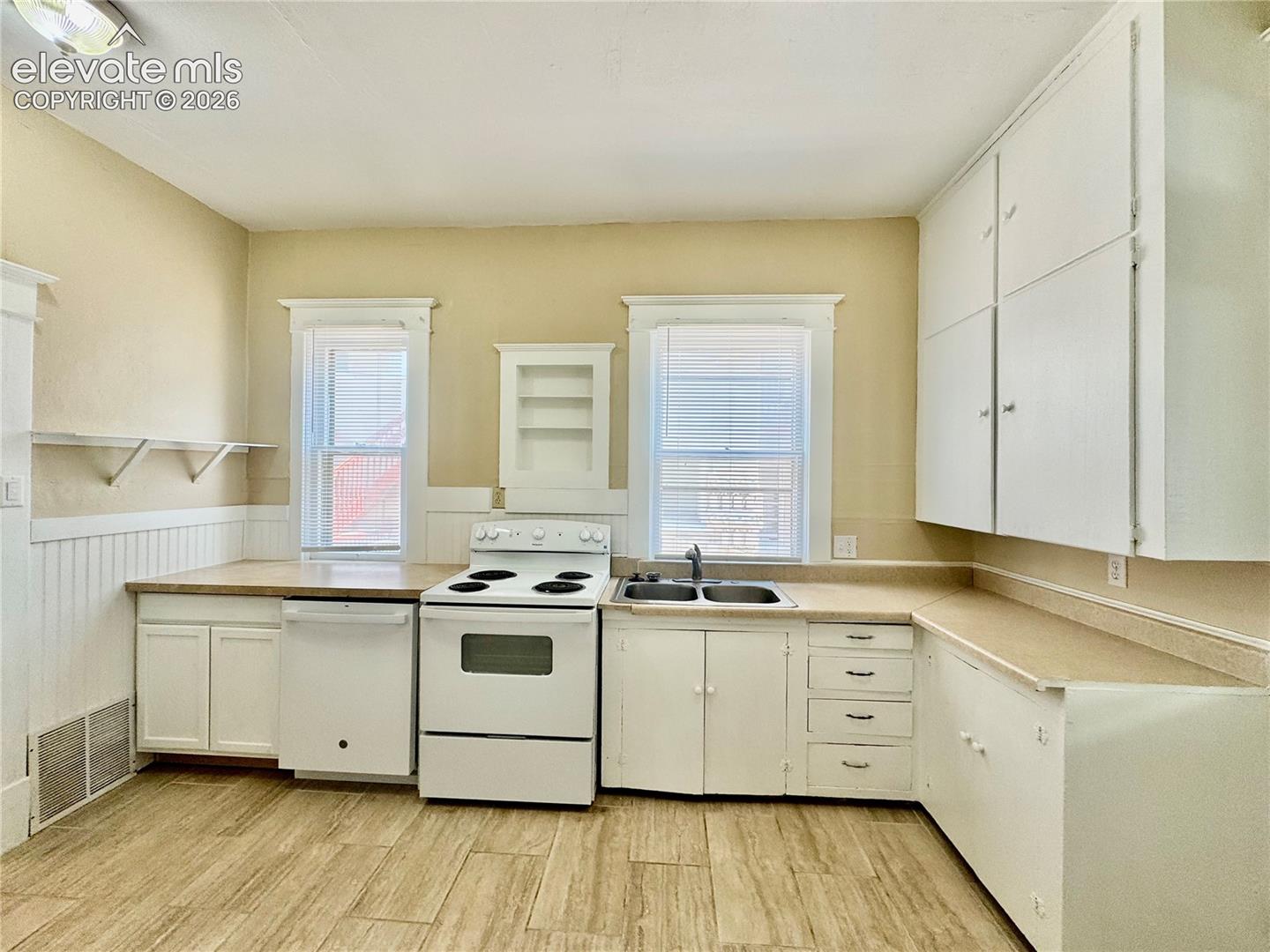 Kitchen featuring wood-finish flooring, white cabinetry, a double basin sink, and a white electric range