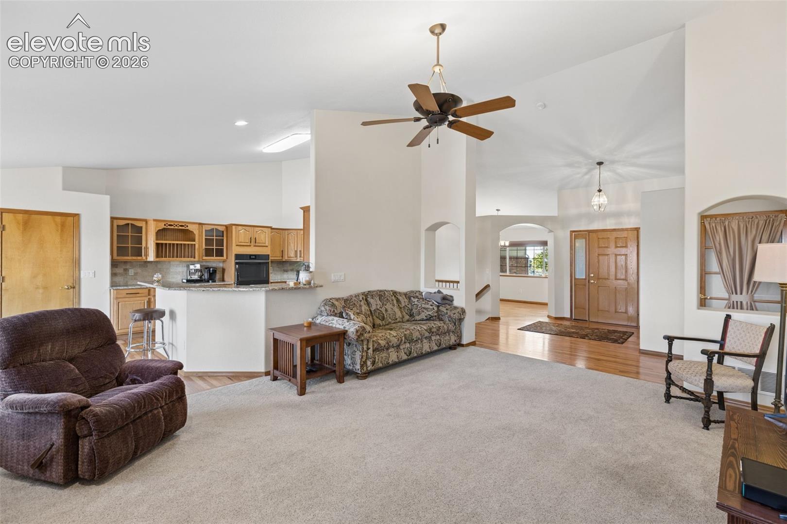 Vaulted ceilings, open-concept kitchen with wood cabinetry and stone countertops, and recessed lighting