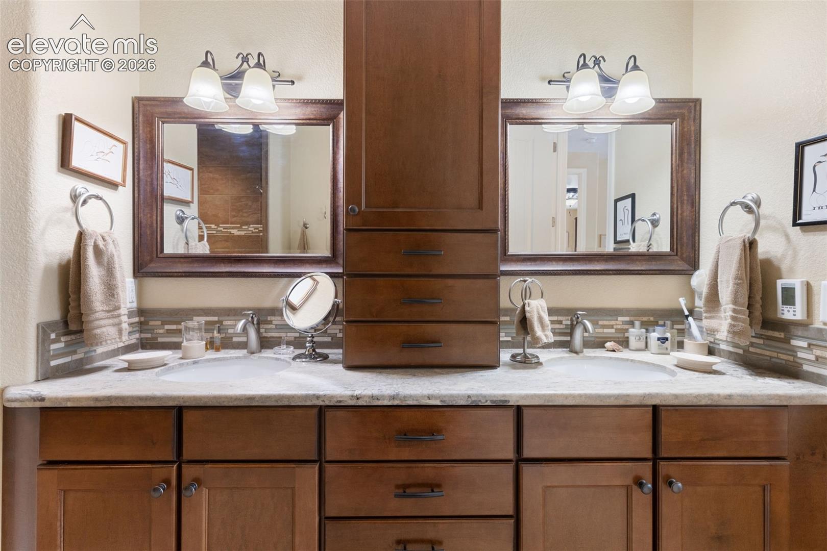 Double vanity featuring individual sinks and mosaic tile backsplash