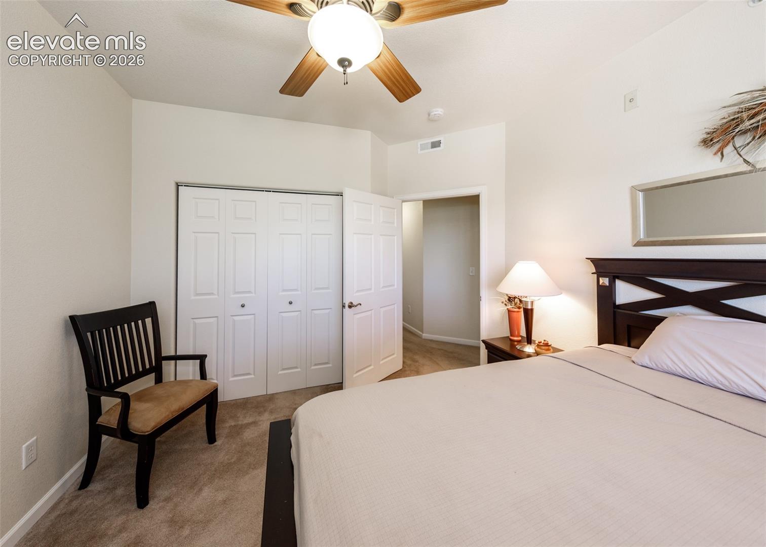 Interior room featuring neutral-toned carpeting, multi-panel closet doors, and a ceiling fan with integrated lighting