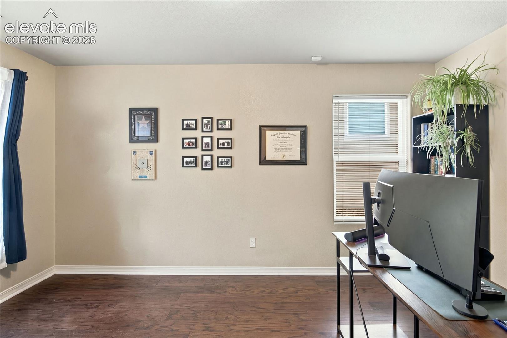 Neutral interior featuring dark wood-finish flooring and a window with horizontal blinds