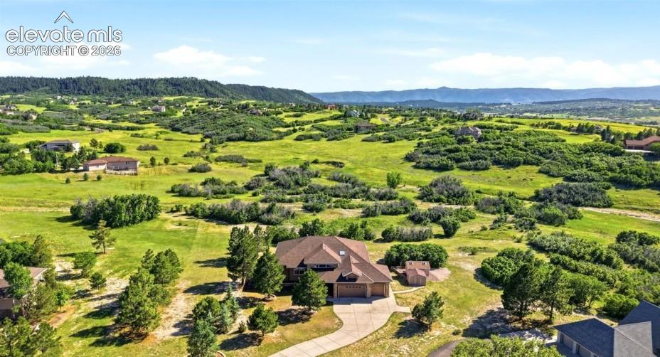 Expansive residential property featuring a paved driveway, natural landscaping, and a mountainous backdrop