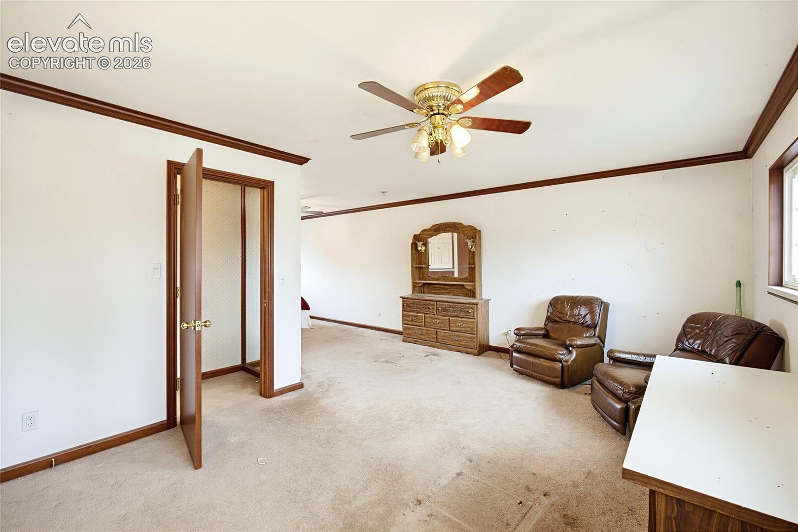 Spacious interior room with carpet flooring, crown molding, and a ceiling fan with integrated lighting
