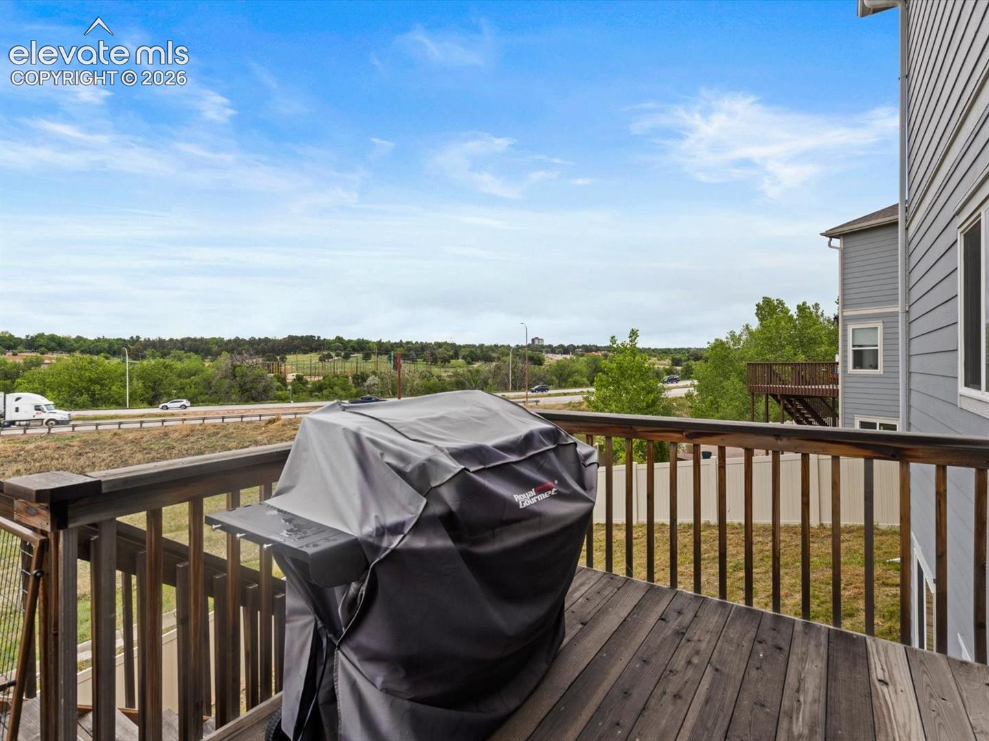 Outdoor deck featuring wood-finish flooring, wood railings, and a partial view of a grey-sided exterior