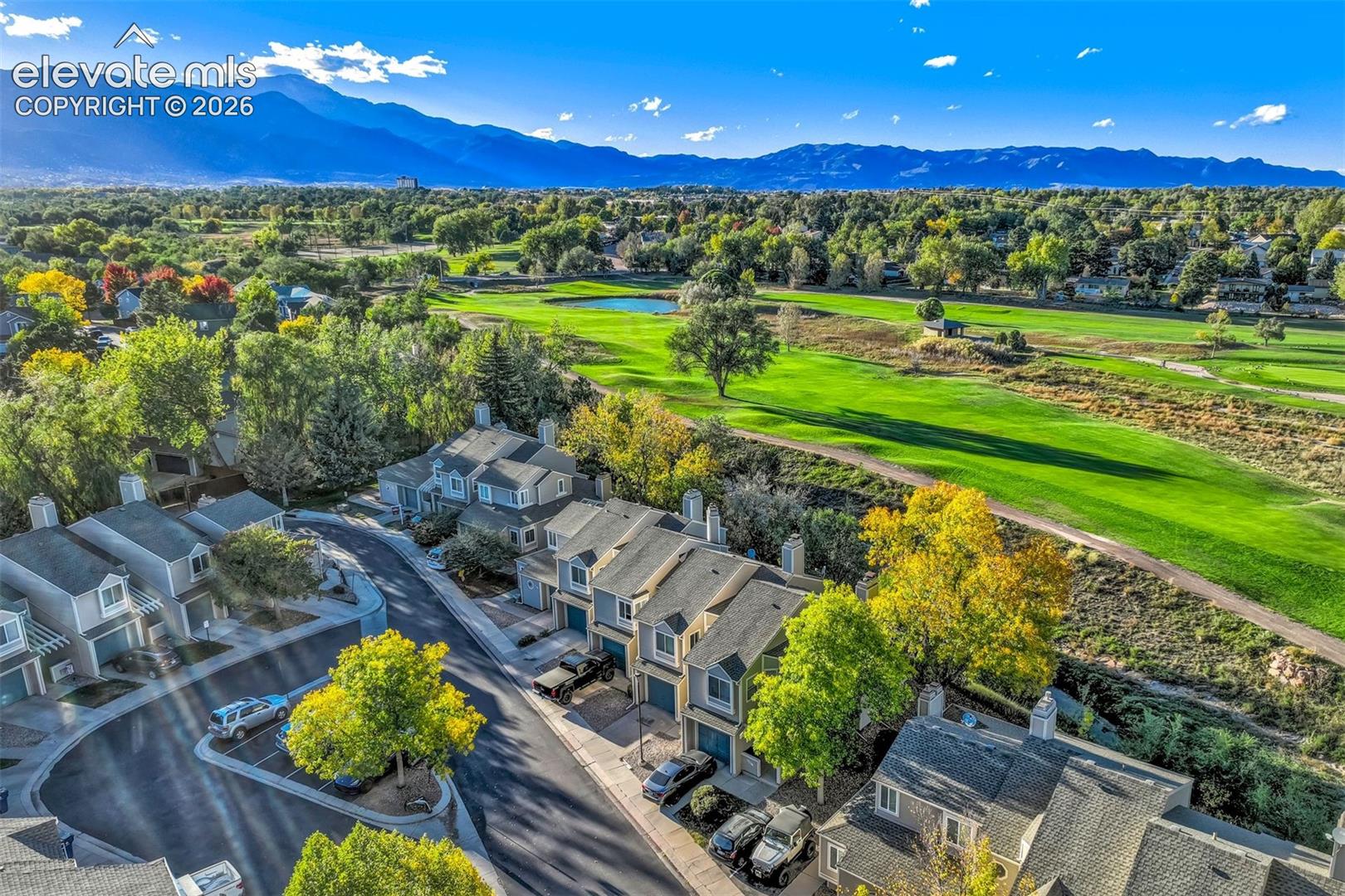Aerial perspective featuring multi-story residential structures with pitched rooflines, asphalt paved driveways, and expansive mountain range surroundings