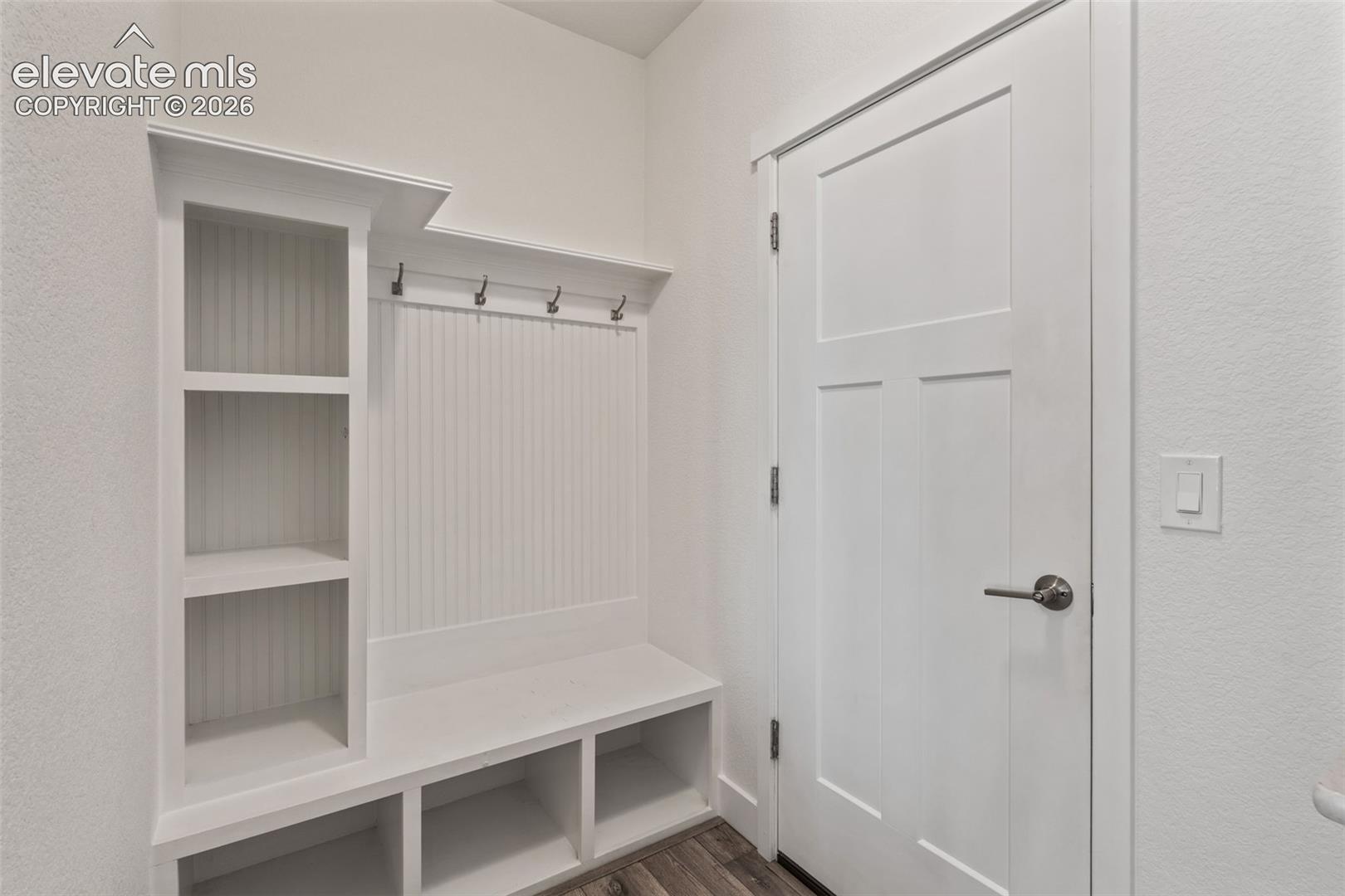 Built-in storage bench with open shelving, beadboard backing, and integrated coat hooks