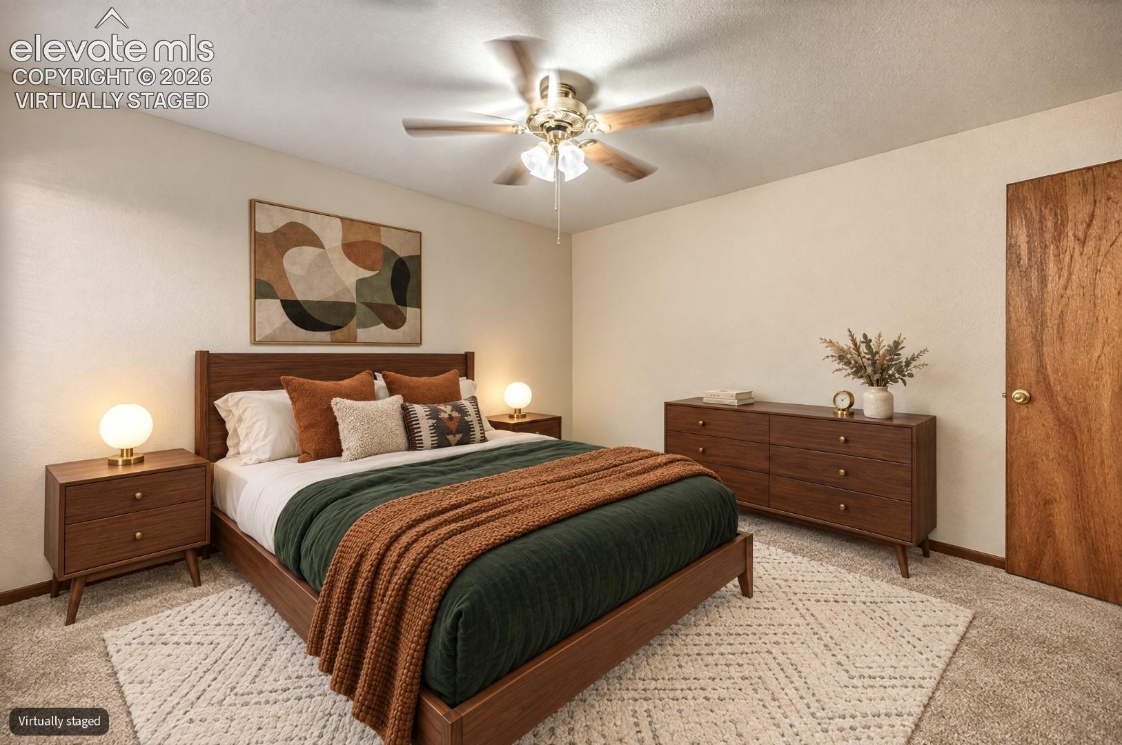 Textured neutral wall paint, ceiling fan with light fixture, wood-finish door, and carpeted flooring - virtually staged 