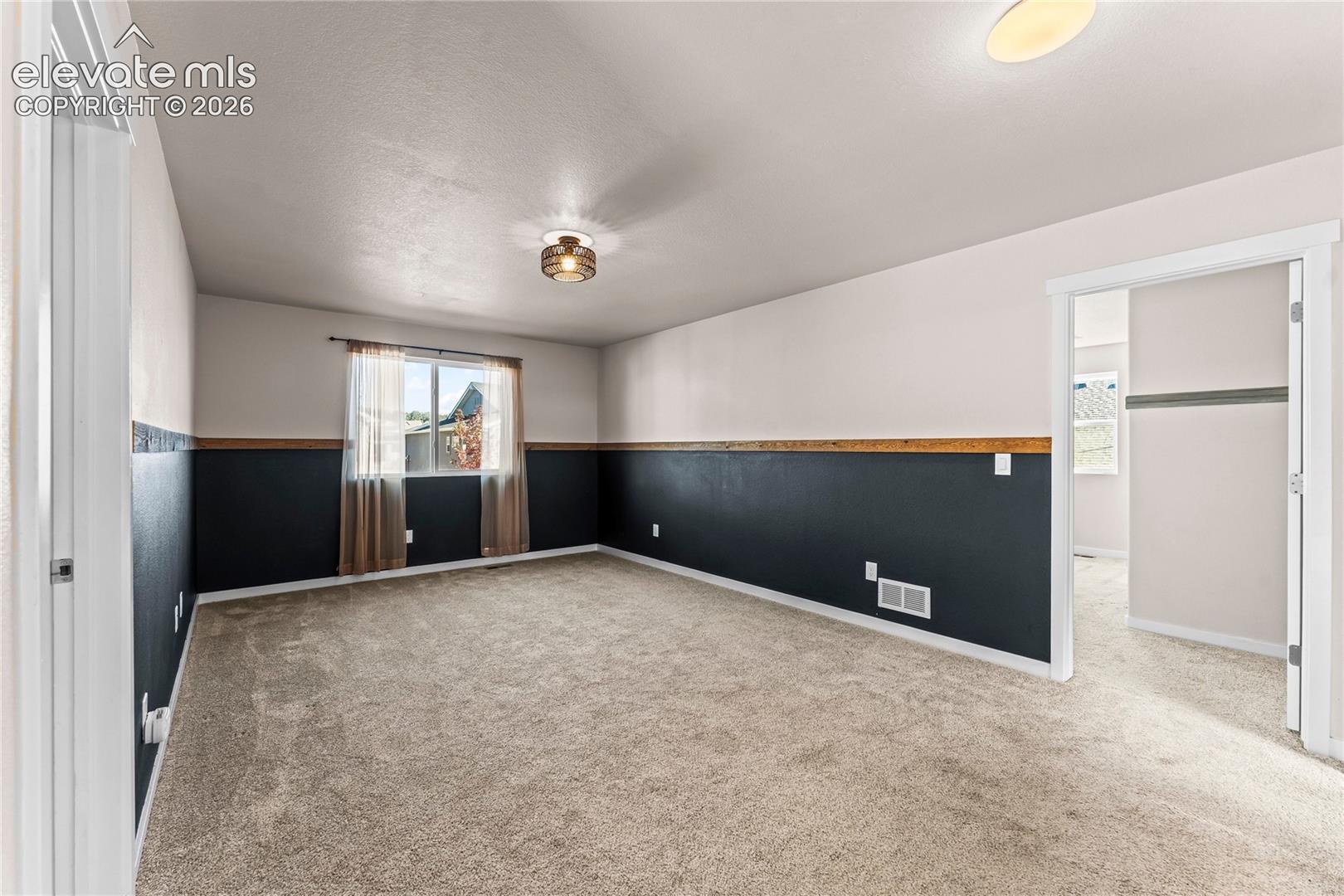 Room featuring neutral carpeting, two-tone walls with wood chair rail trim, and a flush-mount drum ceiling light fixture