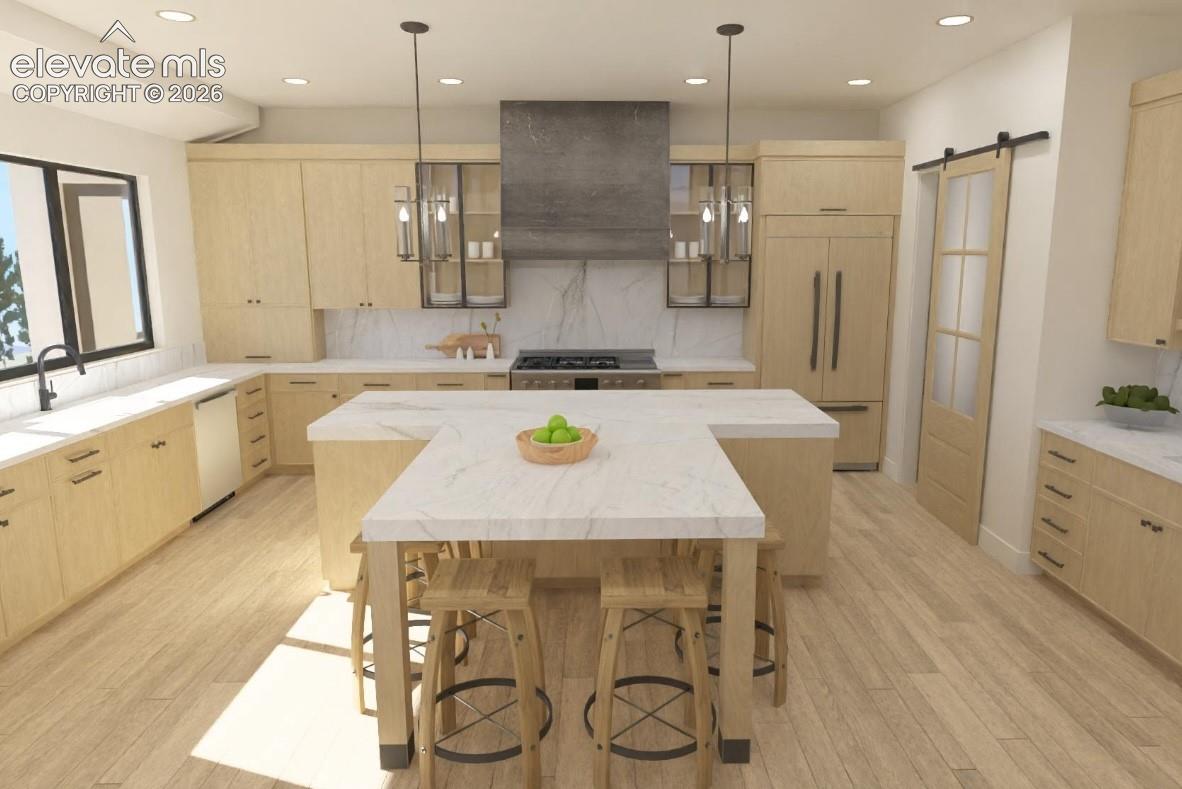 Gourmet kitchen featuring custom wood cabinetry, a large center island with seating, stainless steel appliances, and a sliding barn door