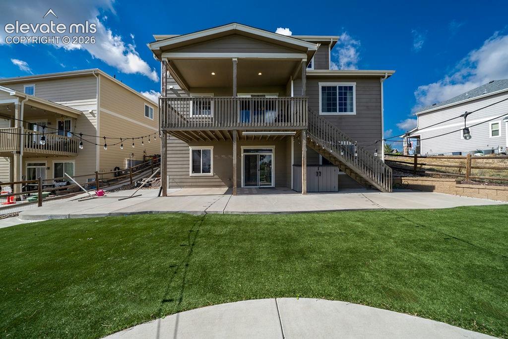 Expansive artificial turf lawn with a concrete patio, wood deck, and walk-out lower level