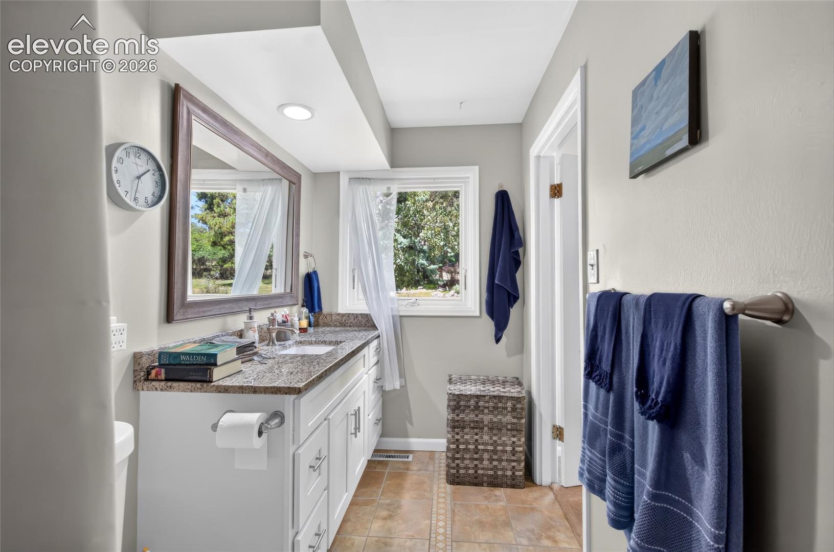 Vanity with a granite-style countertop, undermount sink, and shaker-style cabinetry