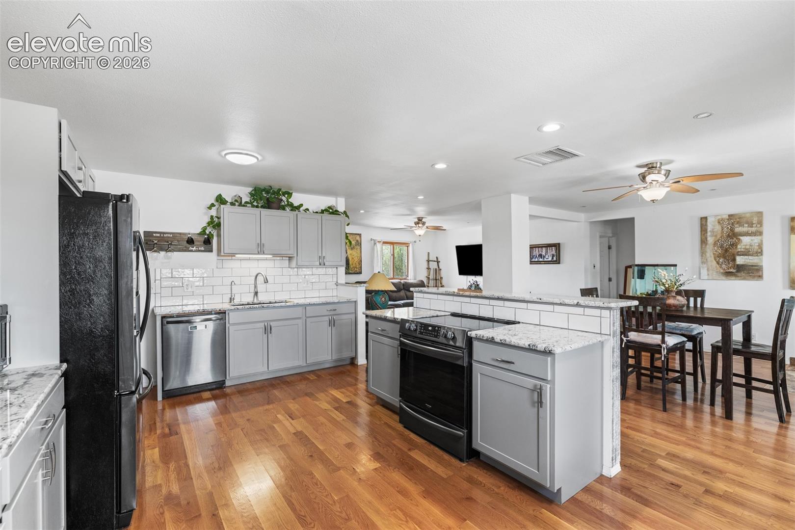 Updated kitchen with granite counter tops, bar seating, black stainless appliances, tile back splash and pantry