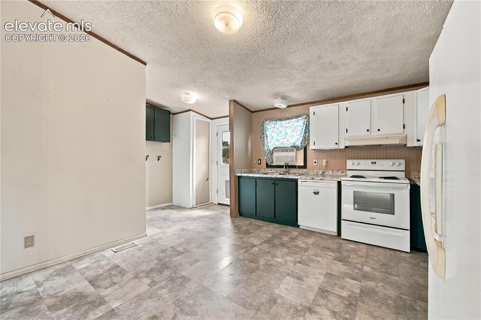 Kitchen featuring white upper cabinetry, dark lower cabinetry, a white electric range, a white dishwasher, and light-toned flooring
