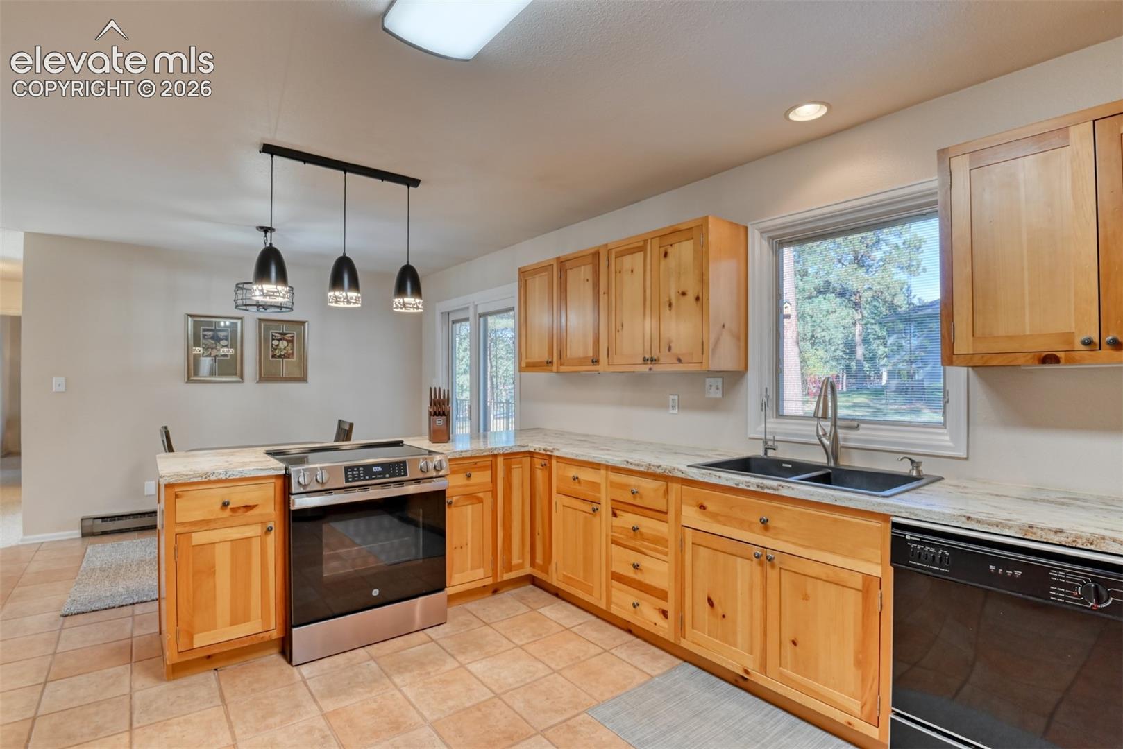 Kitchen featuring pine cabinets, tile floors, stainless steel slide-in range, dual-basin sink, and walks out to the back deck.