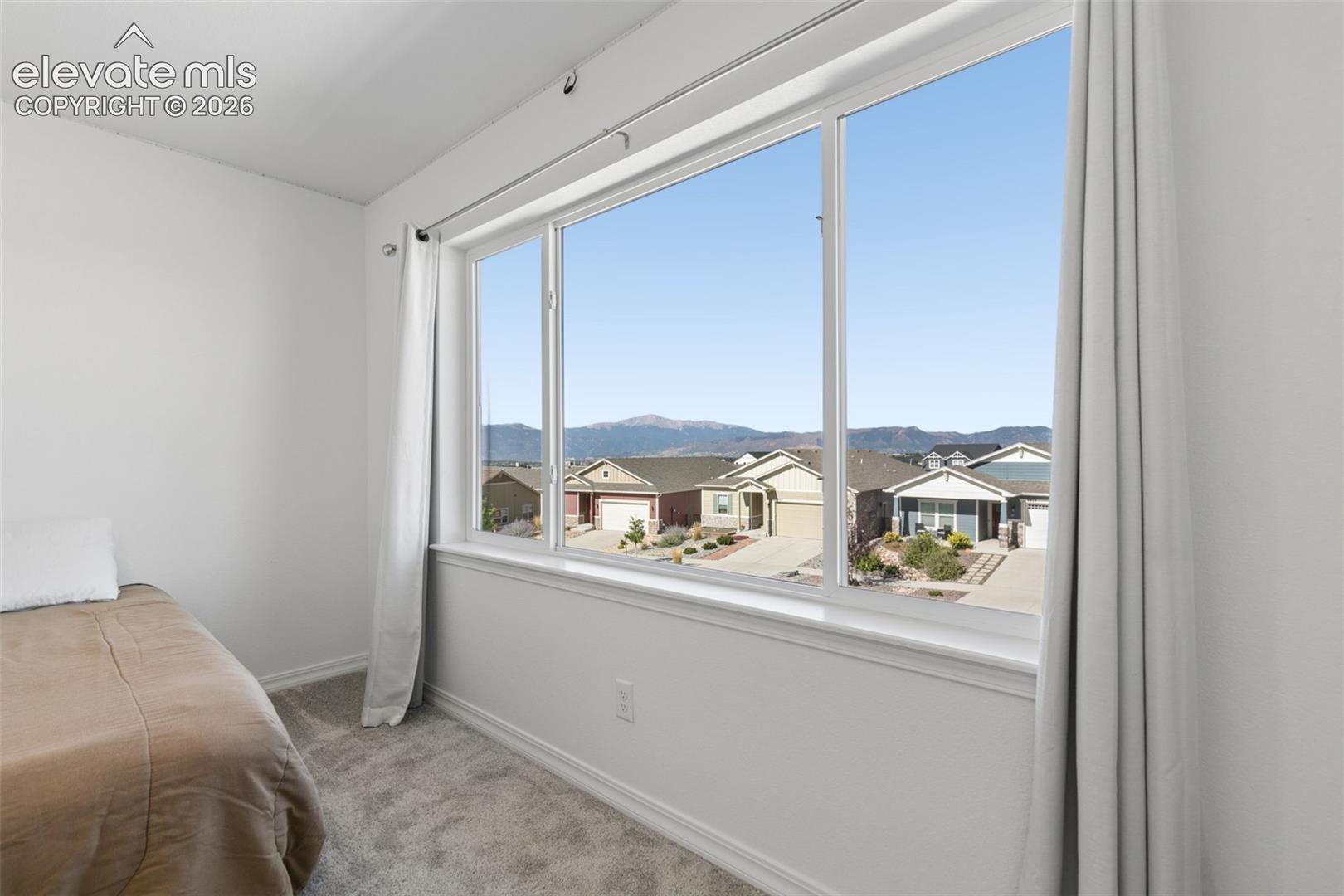 Bright room featuring a large window with mountain view neutral carpeting, and white walls