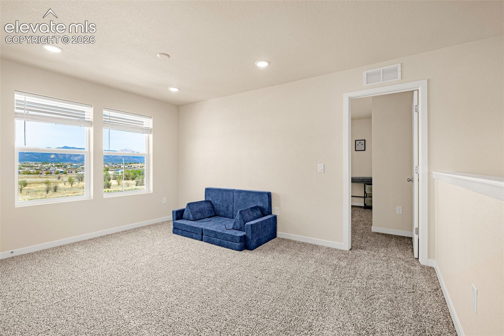 Recessed lighting illuminates the carpeted interior, featuring multiple windows with blinds and an open doorway