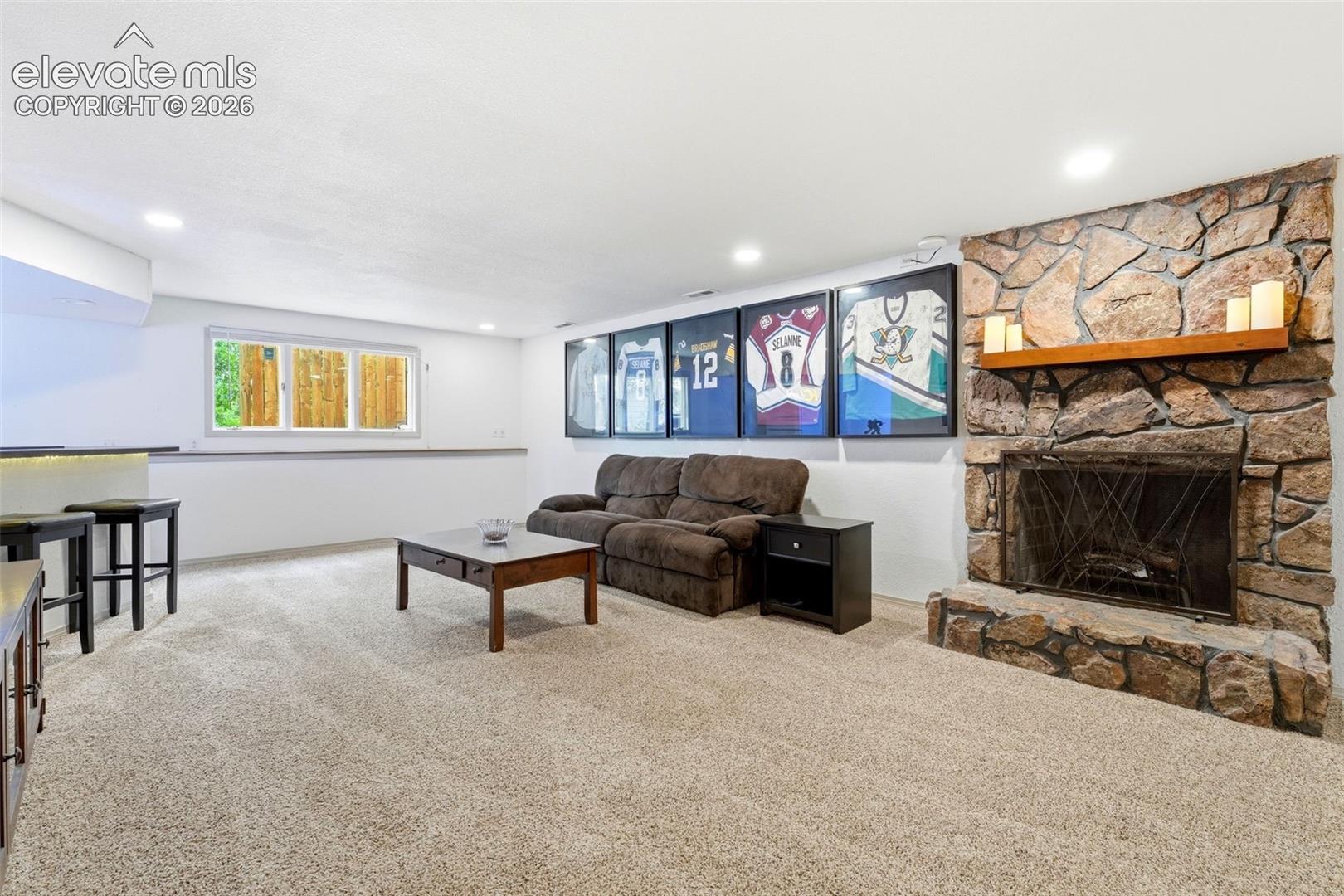 Rec room with Stone-clad fireplace with a wood mantel, built-in bar, and media space 