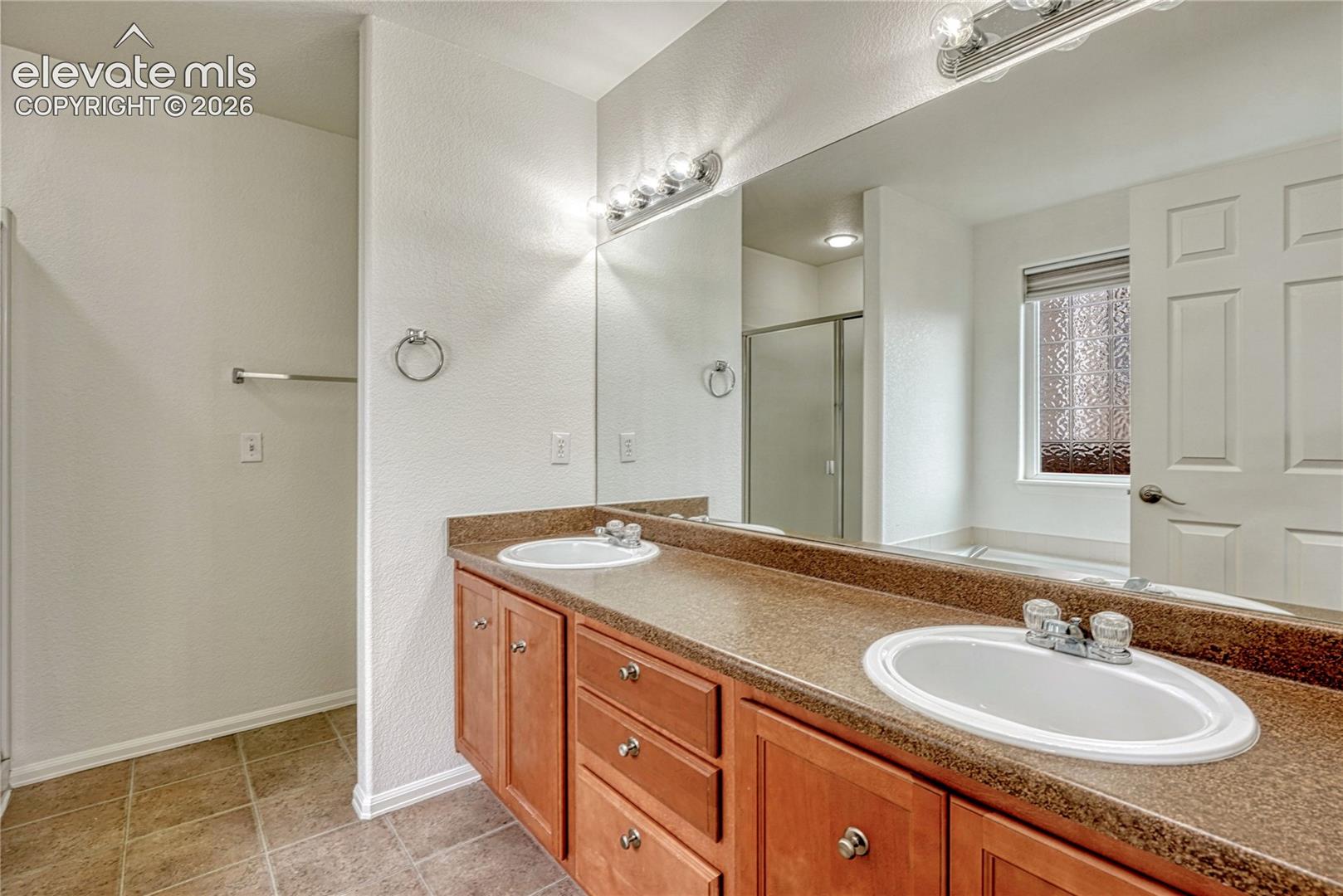Primary 5-piece bathroom with double vanity.