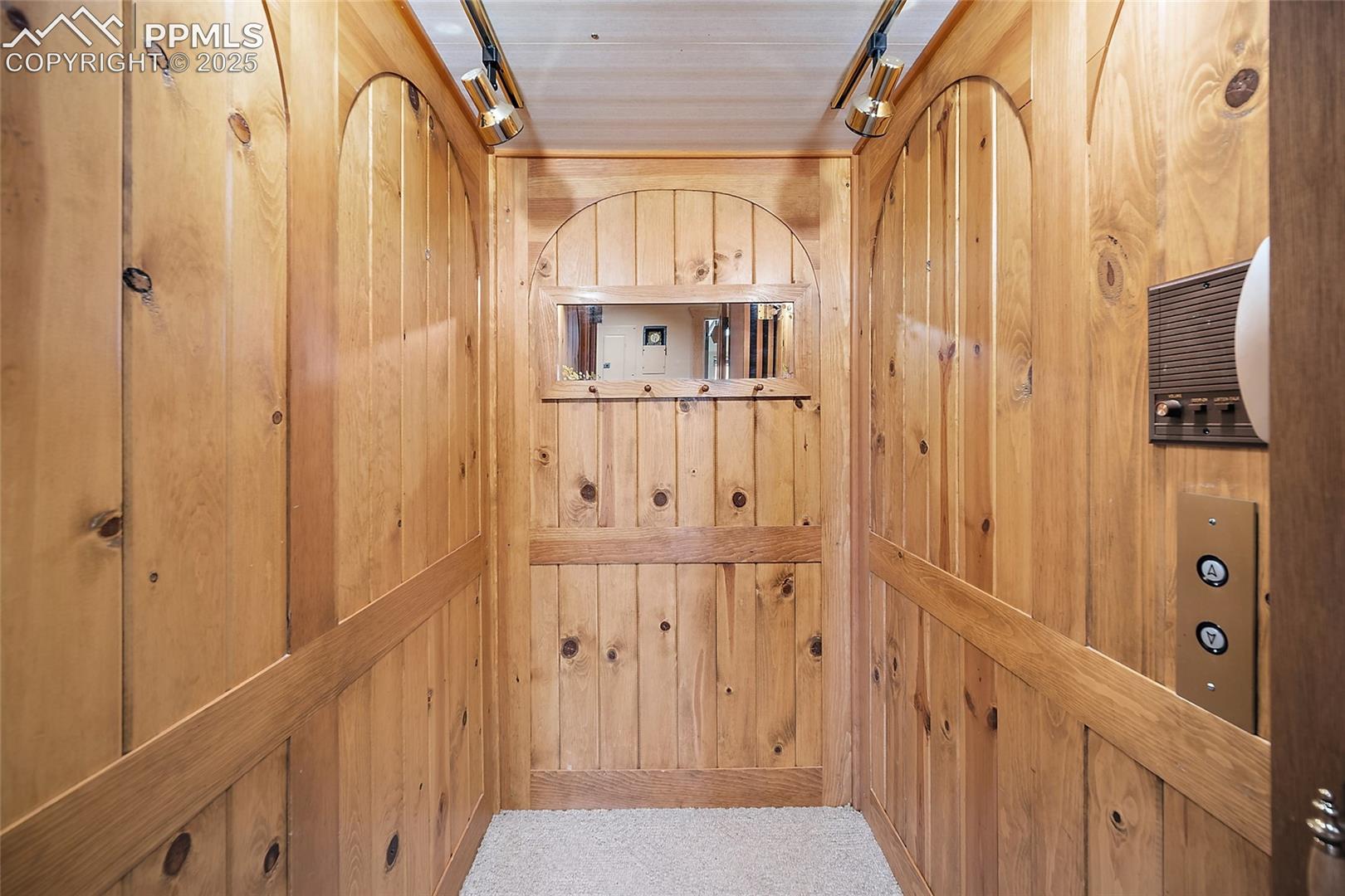 Elevator featuring wooden walls and track lighting