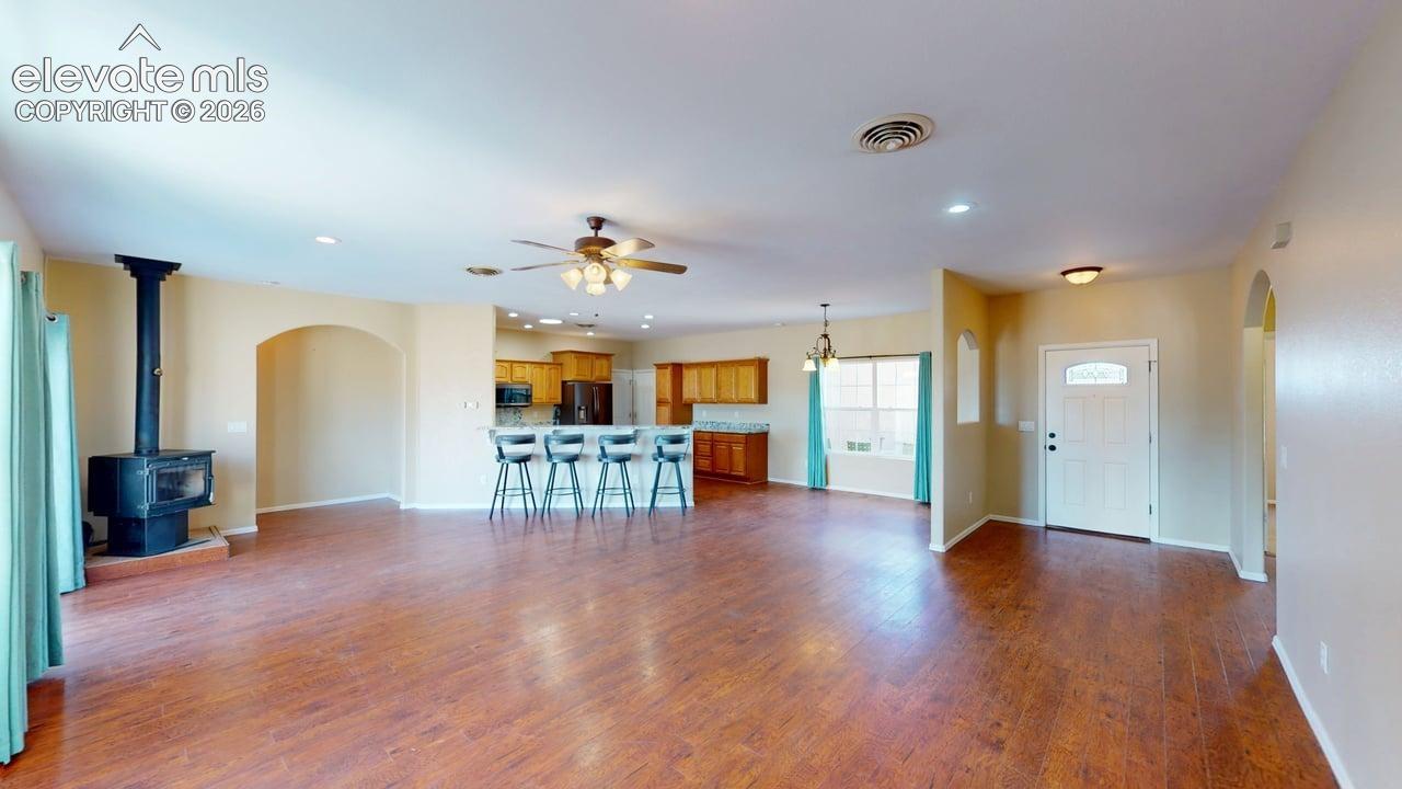 Expansive living area featuring wood-finish flooring, a freestanding wood-burning stove, and a ceiling fan