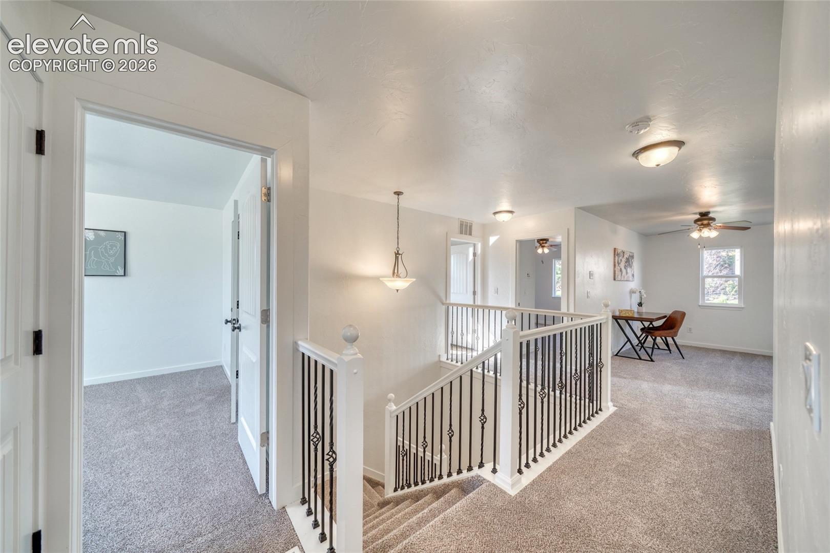 Carpeted staircase with decorative metal balusters and white newel posts