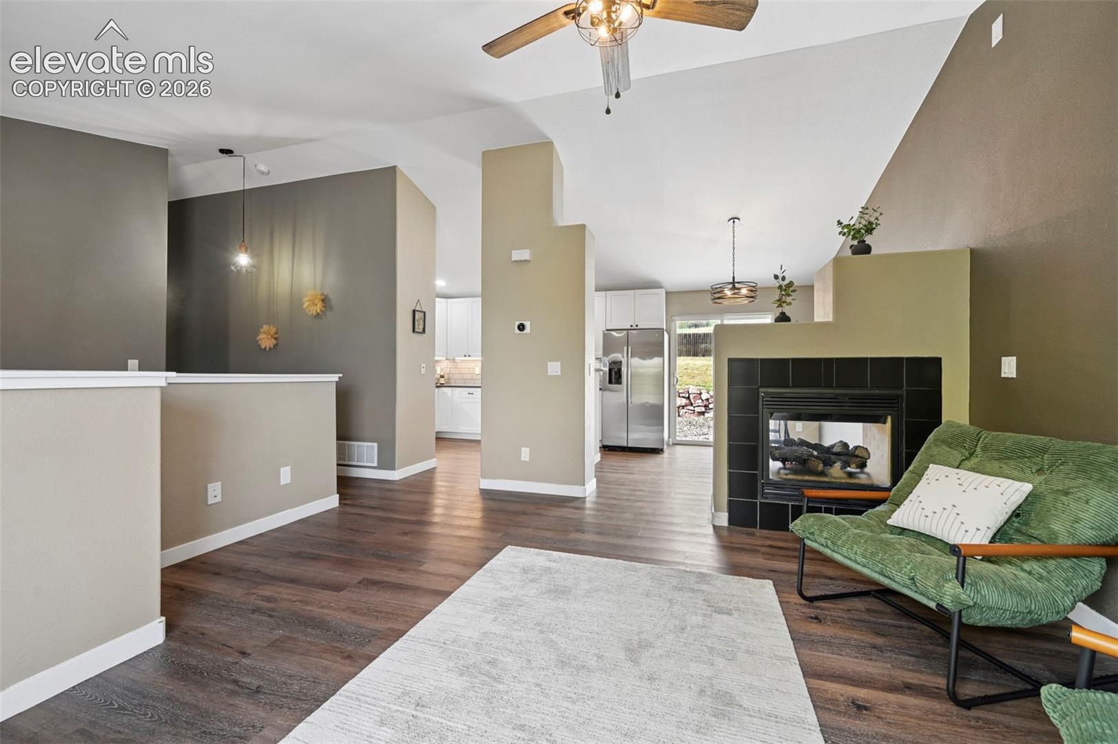 Vaulted ceilings featuring a ceiling fan, wood-finish flooring and fireplace
