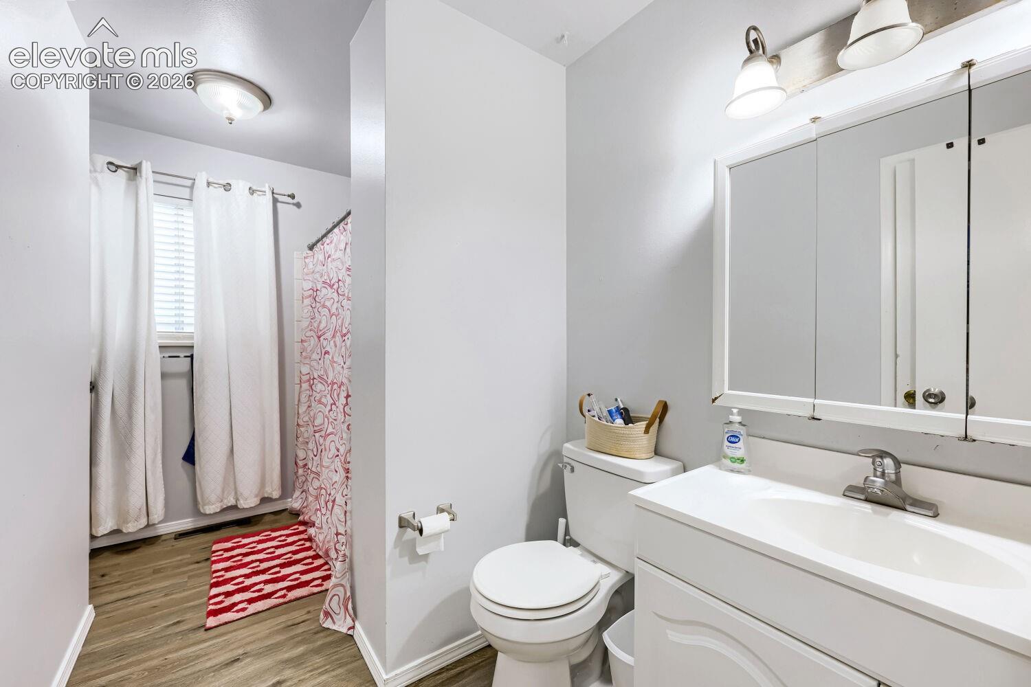 White vanity with integrated sink, chrome faucet, and mirrored medicine cabinet