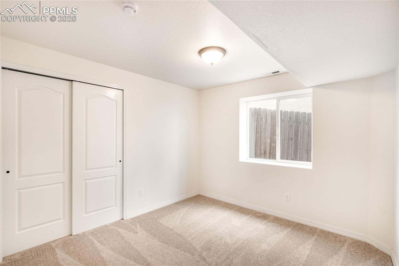 Second basement bedroom featuring a single window and closet with sliding doors