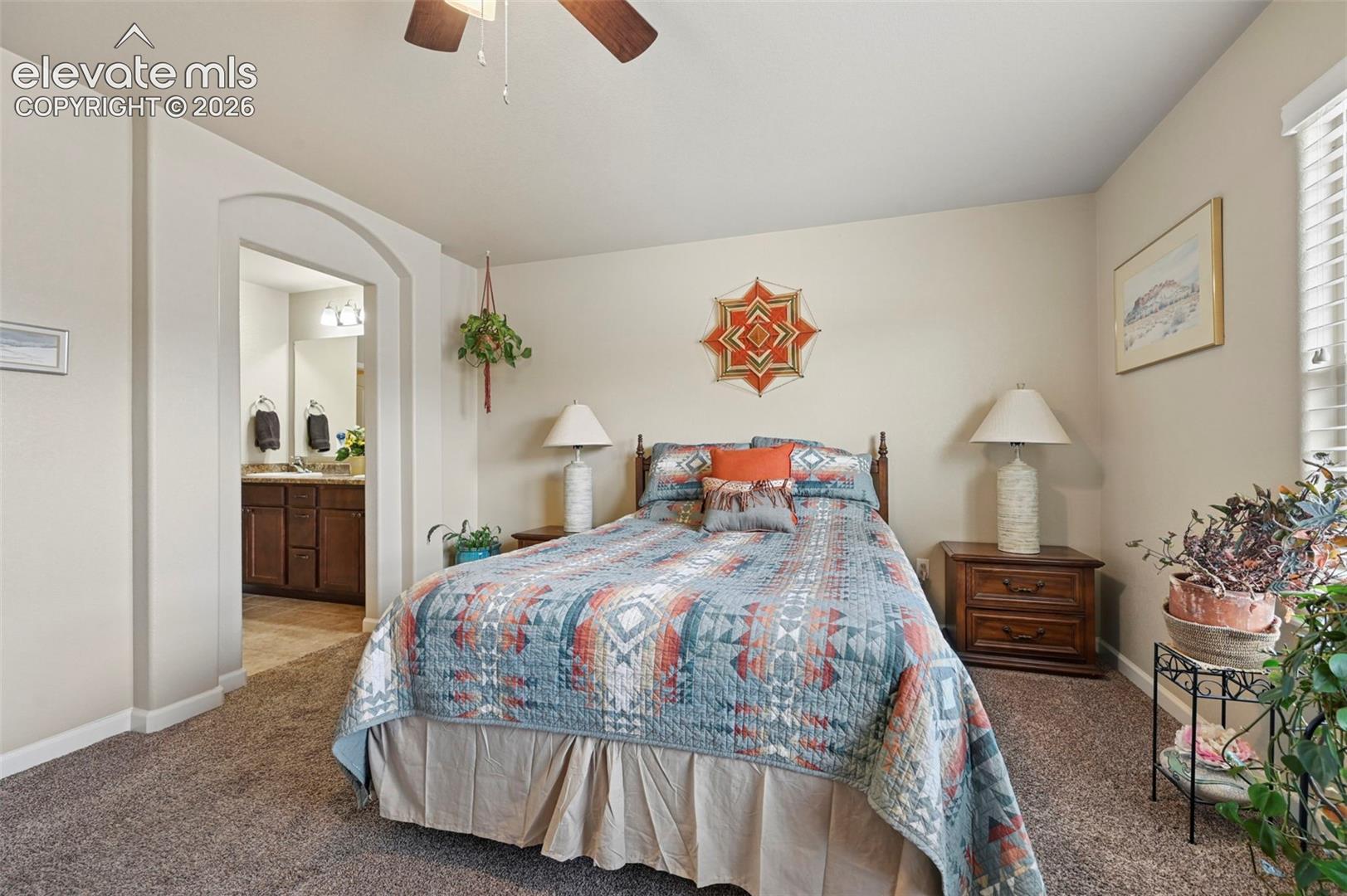 Carpeted room featuring an arched doorway leading to an adjoining bathroom