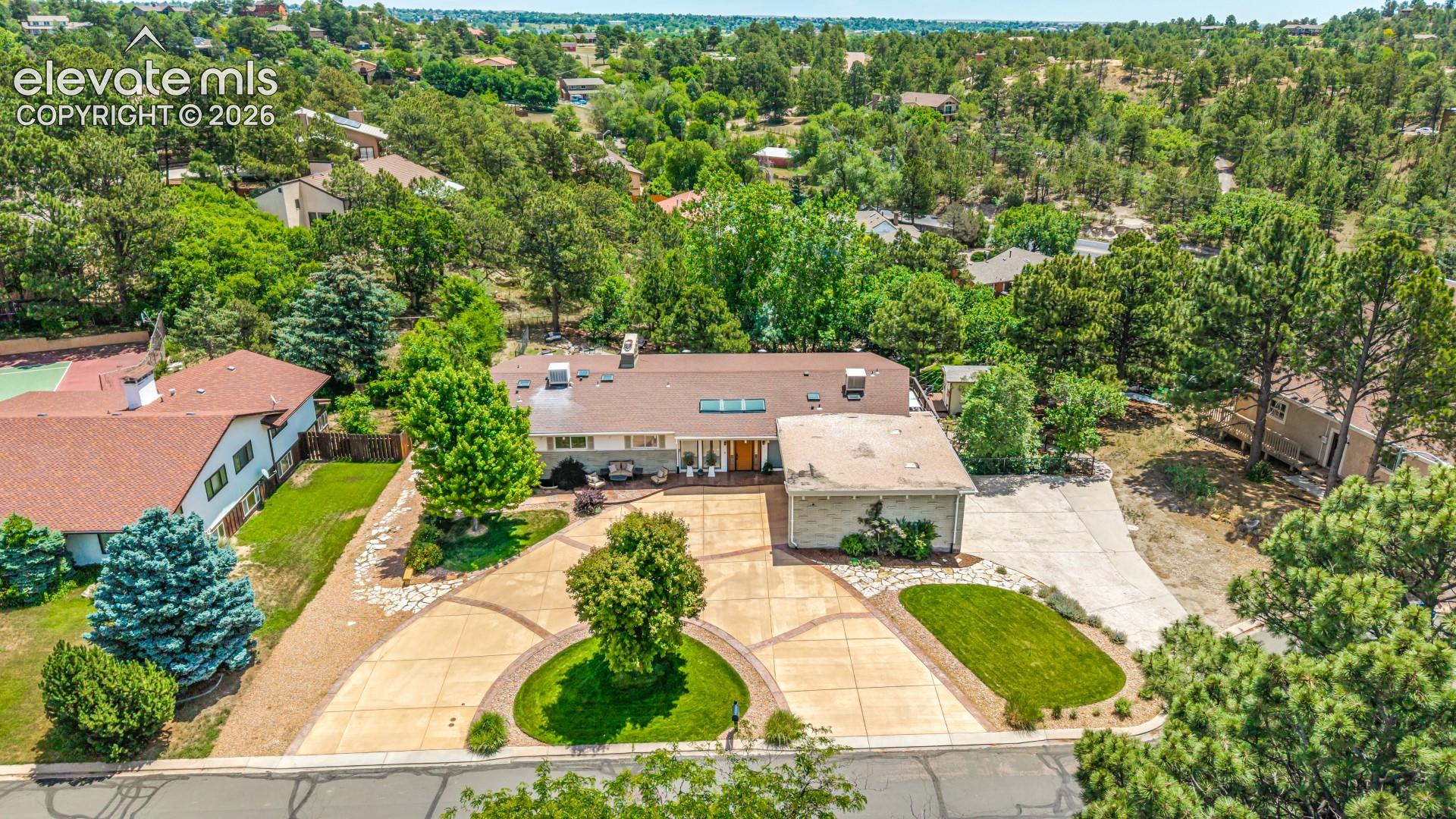 An aerial view reveals the full scope of the property, from the circular motor court out front to the wooded lot stretching behind the home.