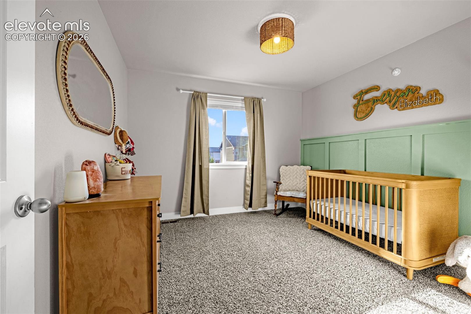 Light-filled room featuring plush gray carpeting and a paneled accent wall
