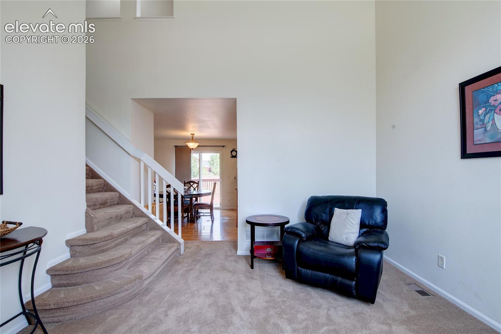 Carpeted entryway with a curved staircase featuring white railings