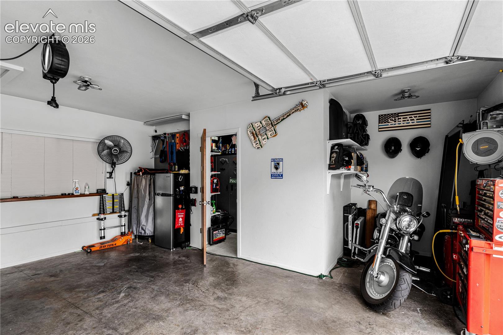 Attached garage featuring concrete flooring, an automated overhead door system, a ceiling-mounted fan, and an integrated storage closet