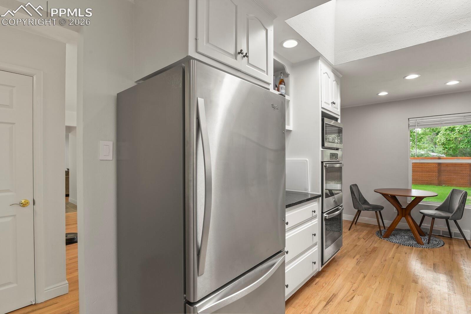 Kitchen featuring a stainless steel refrigerator, white cabinetry and integrated stainless steel double ovens