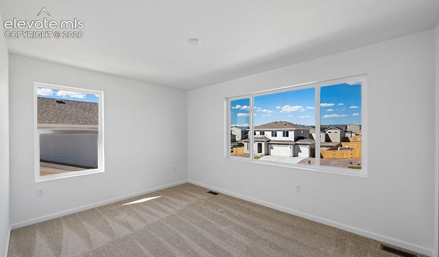 Neutral-toned wall-to-wall carpeting and expansive windows with custom white frames