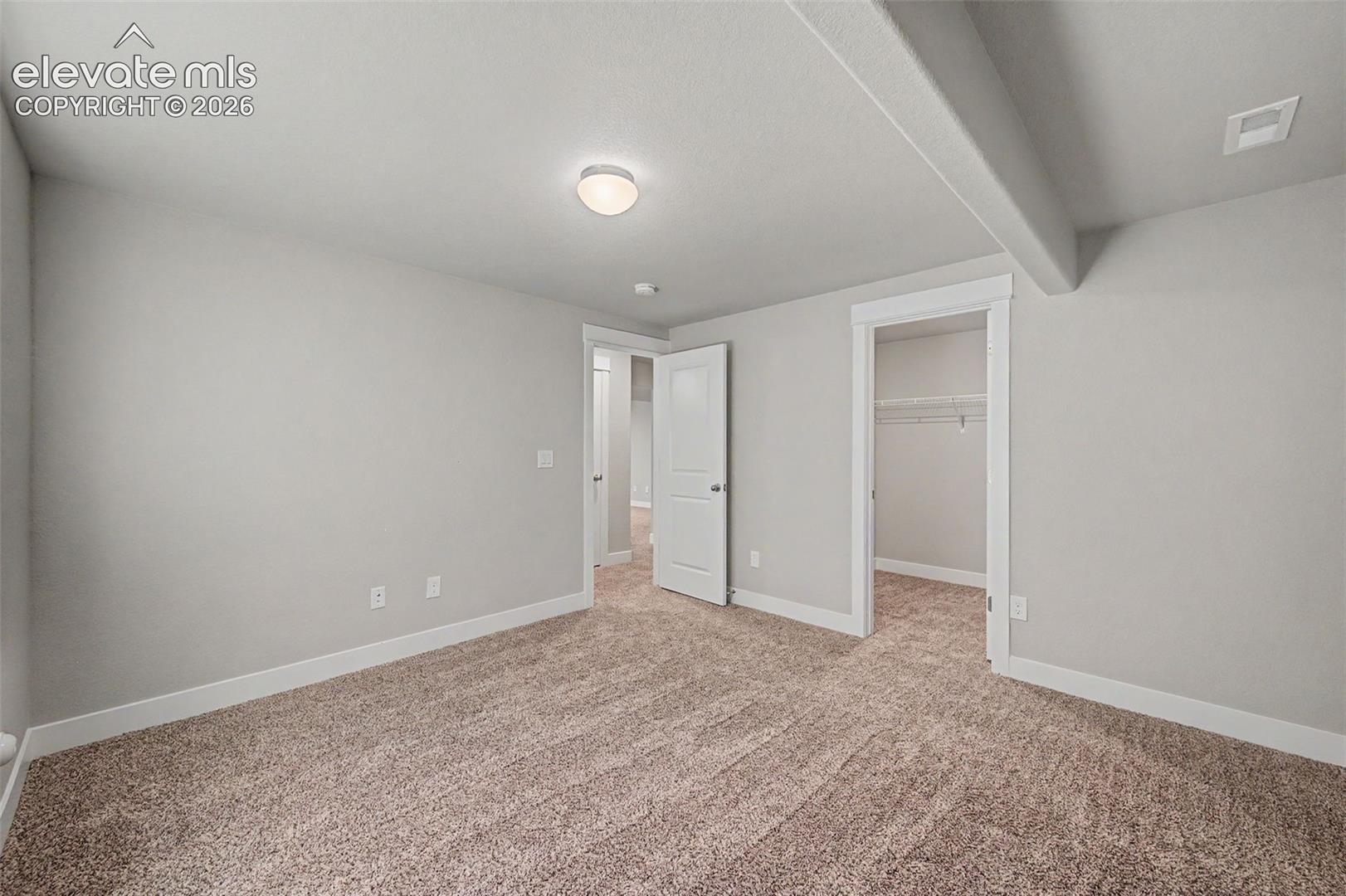 Carpeted room featuring light gray walls, white baseboards, and a flush-mount ceiling light