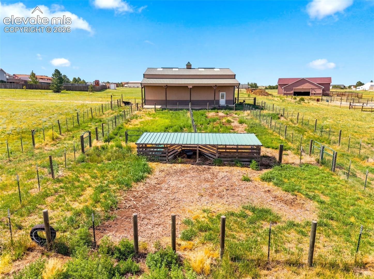 Expansive rural property featuring multiple fenced pastures, a substantial barn structure with covered overhang, and additional outbuildings