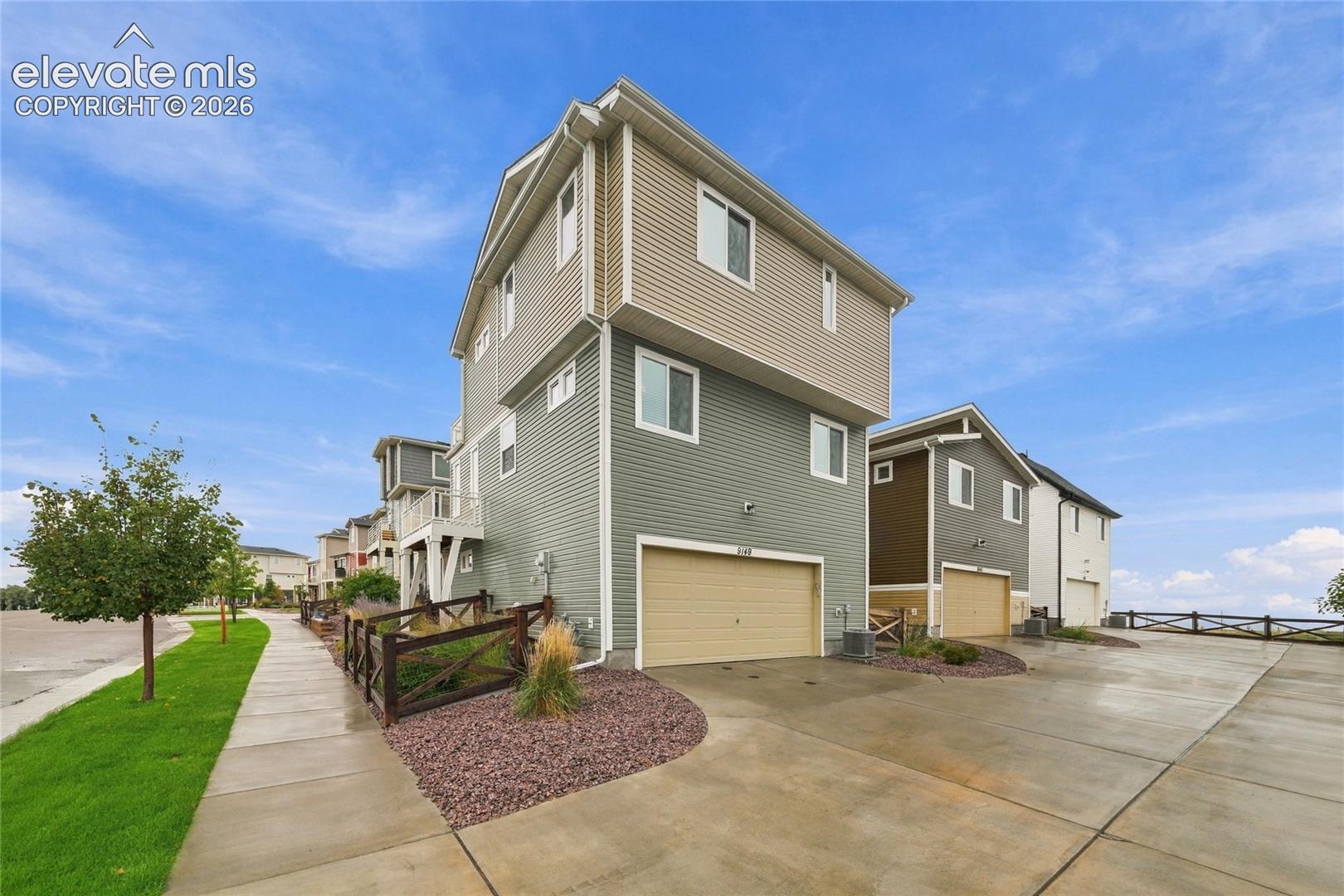 Three-story residence featuring multi-tone siding and an attached garage