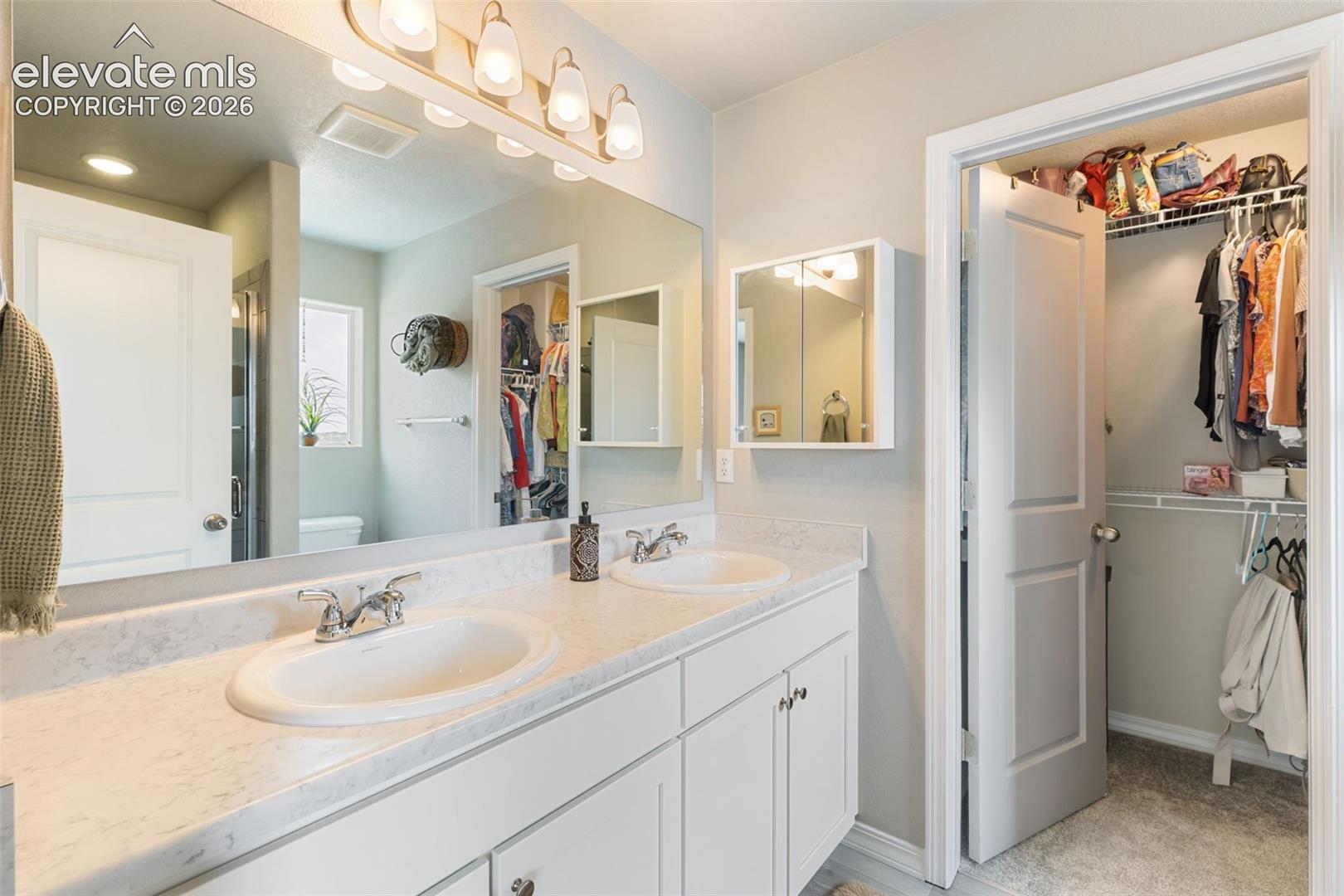 Double vanity featuring integrated sinks, chrome faucets, and a light-toned countertop