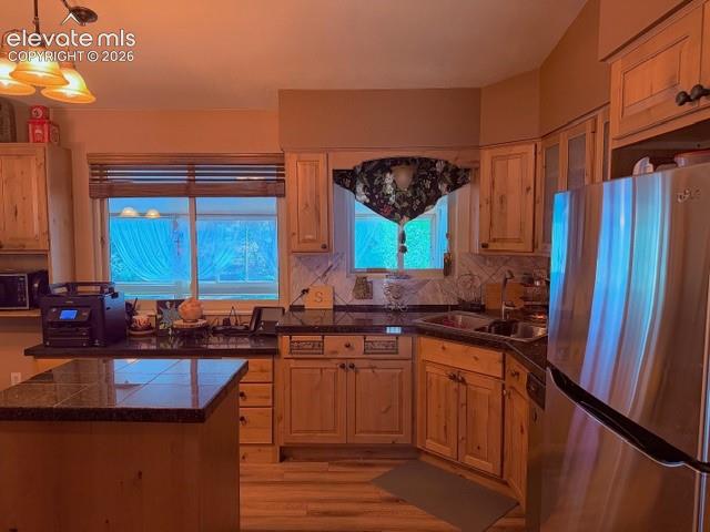 Kitchen featuring natural wood cabinetry, dark granite countertops, and tile flooring