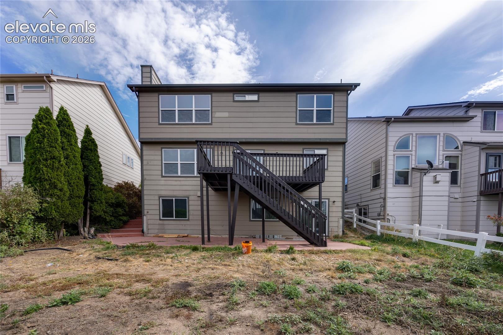 Two-story exterior with a ground-level patio and an elevated deck with stairs