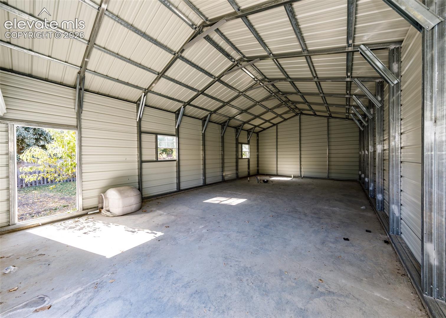 Detached structure featuring a metal frame, corrugated metal walls and roof, concrete flooring, and multiple inset windows