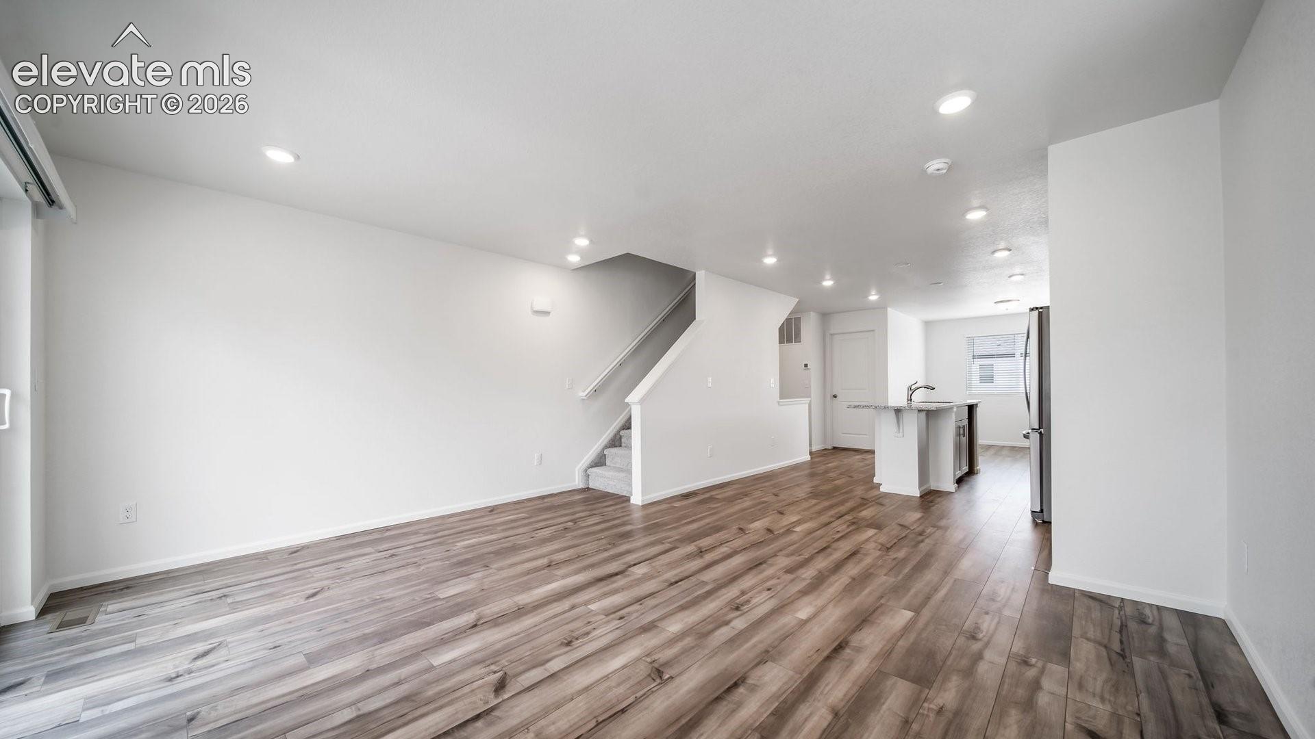 Open-concept living area featuring wood-finish flooring, recessed lighting, and a sliding glass door
*photos of a model home*