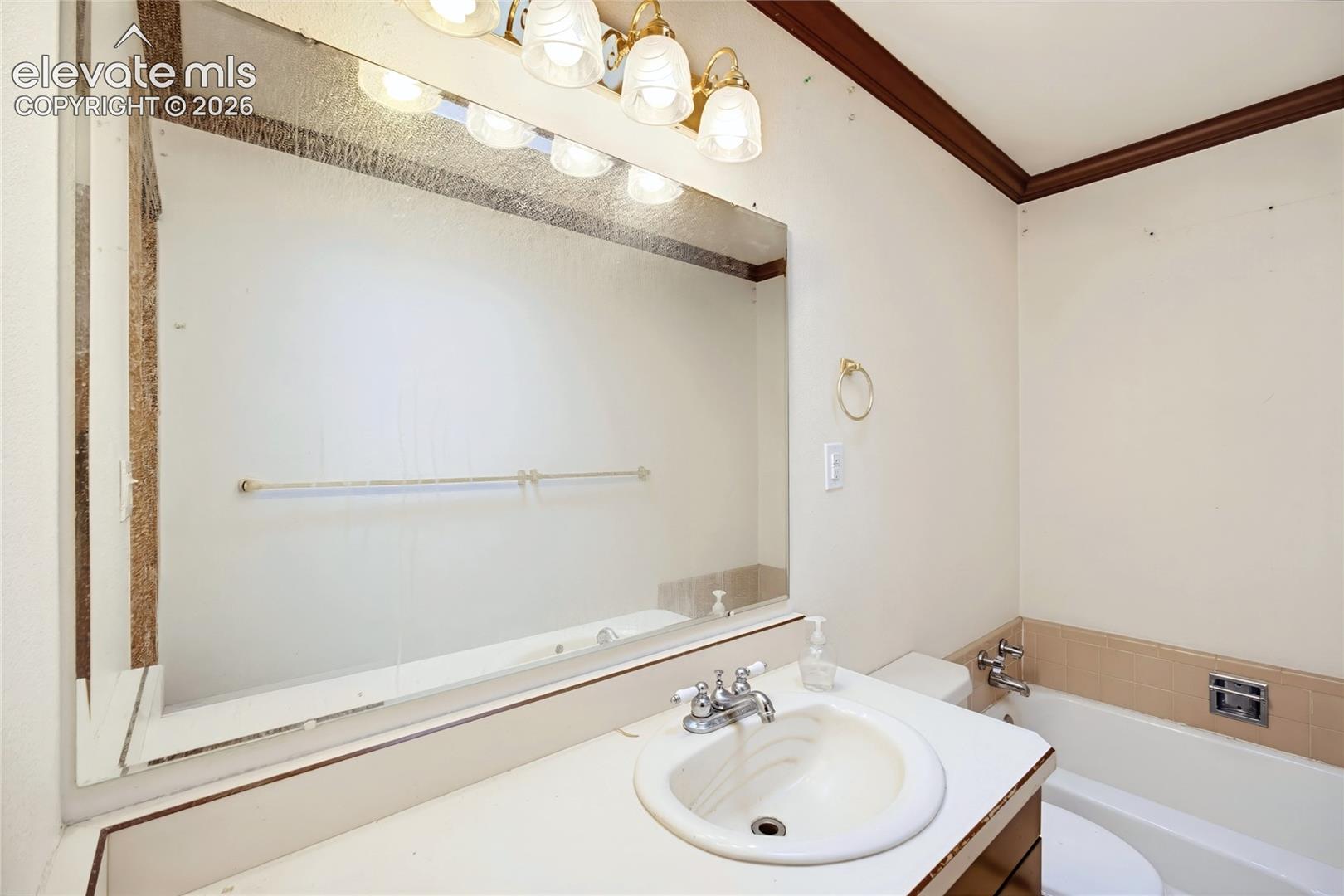 Vanity with integrated sink, chrome-finish faucet, and expansive wall-mounted mirror