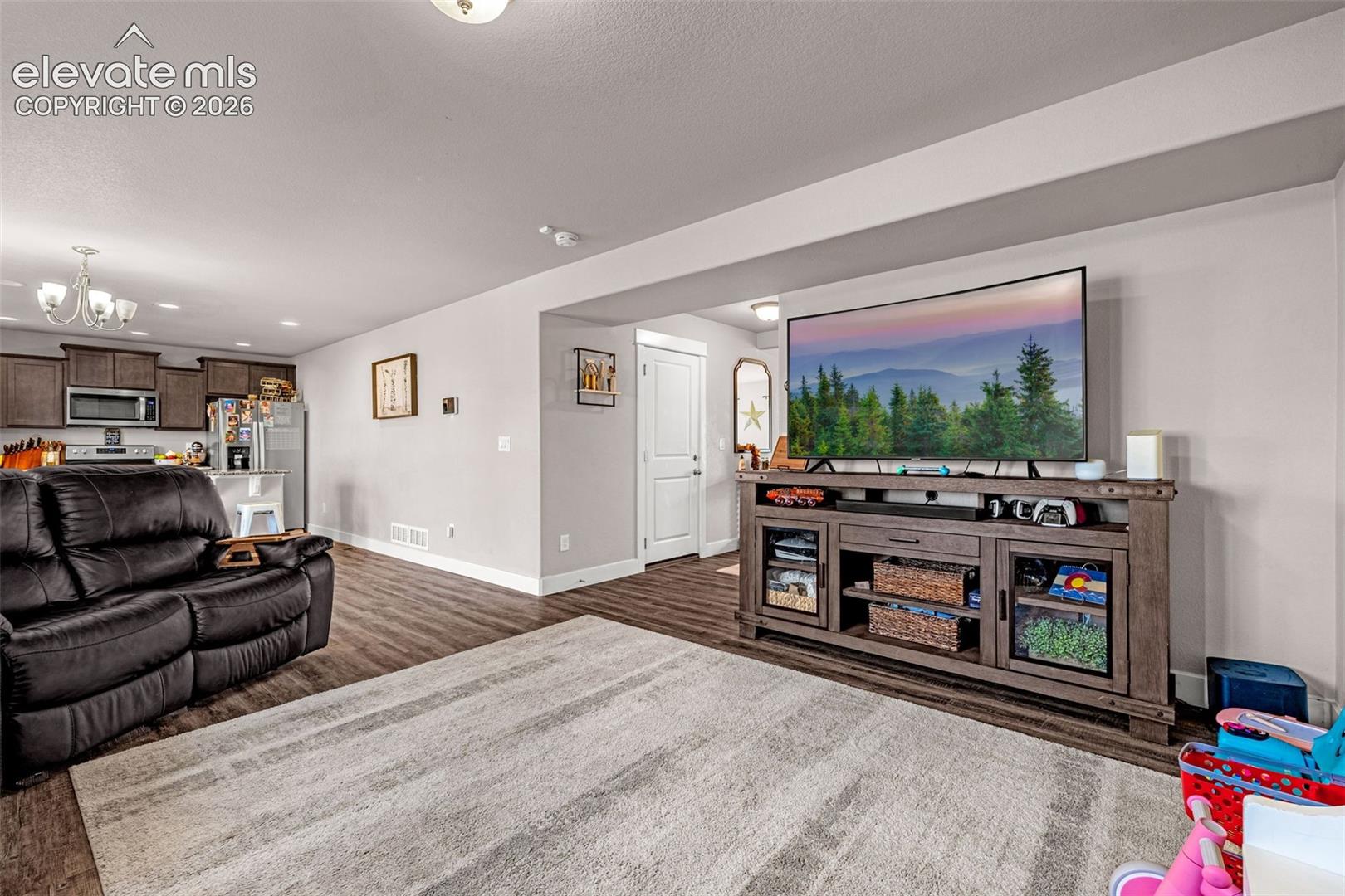 Spacious open-concept living area featuring wood-finish flooring, recessed lighting, and a neutral color palette
