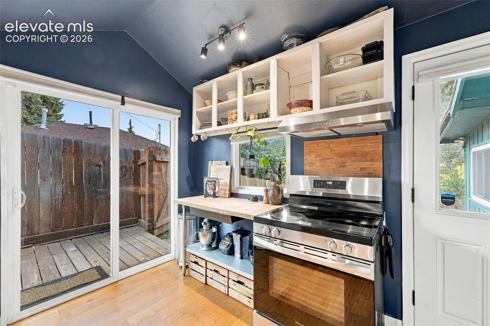 Kitchen featuring stainless steel range with overhead vent hood.