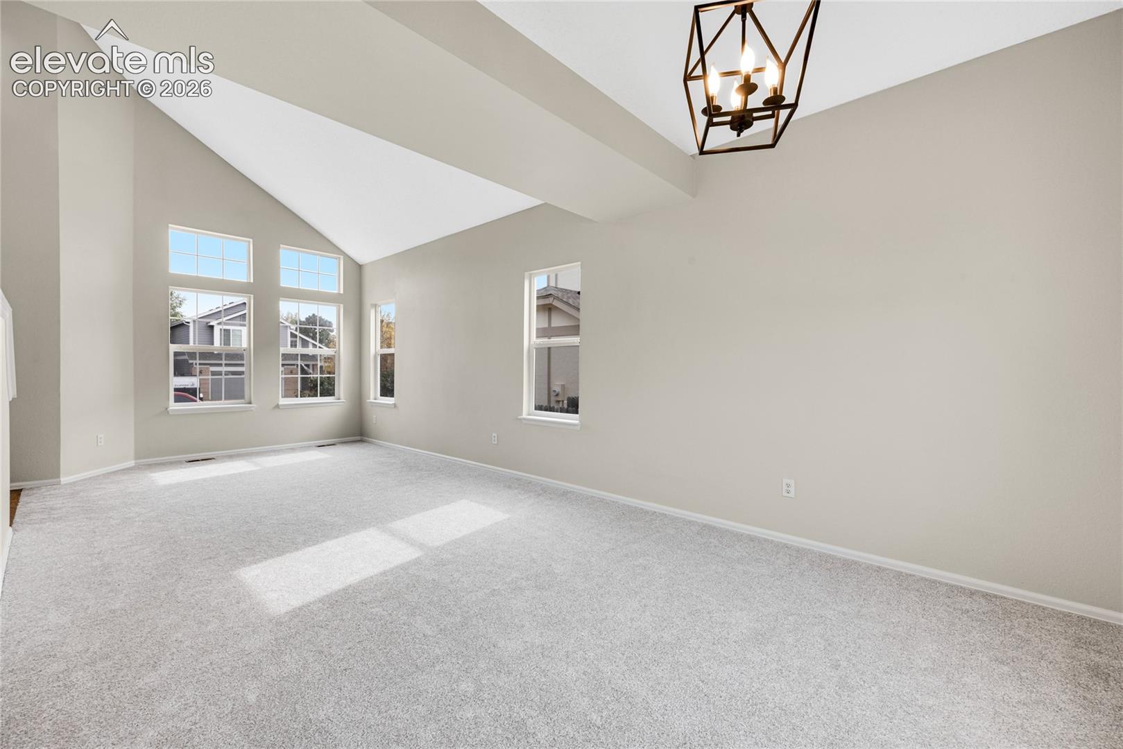 Vaulted ceilings, geometric pendant light fixture, and multiple windows with white trim