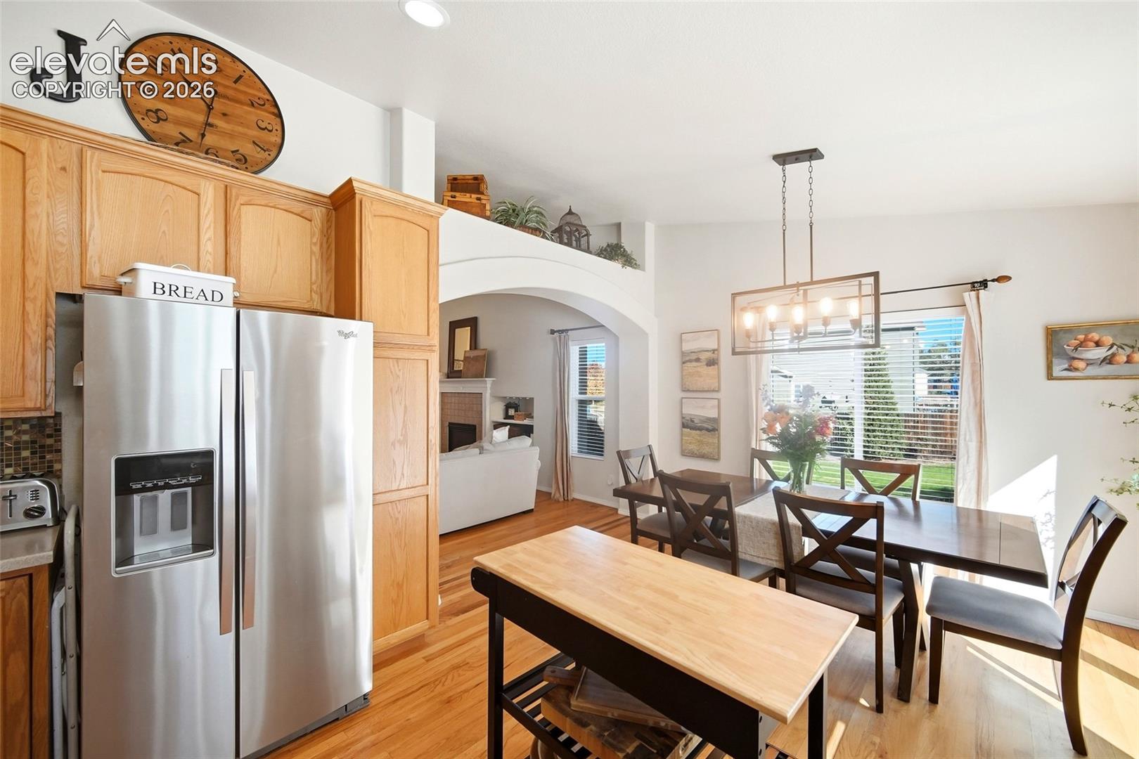 Open-concept kitchen and dining area featuring wood-finish flooring, stainless steel appliances, and wood cabinetry