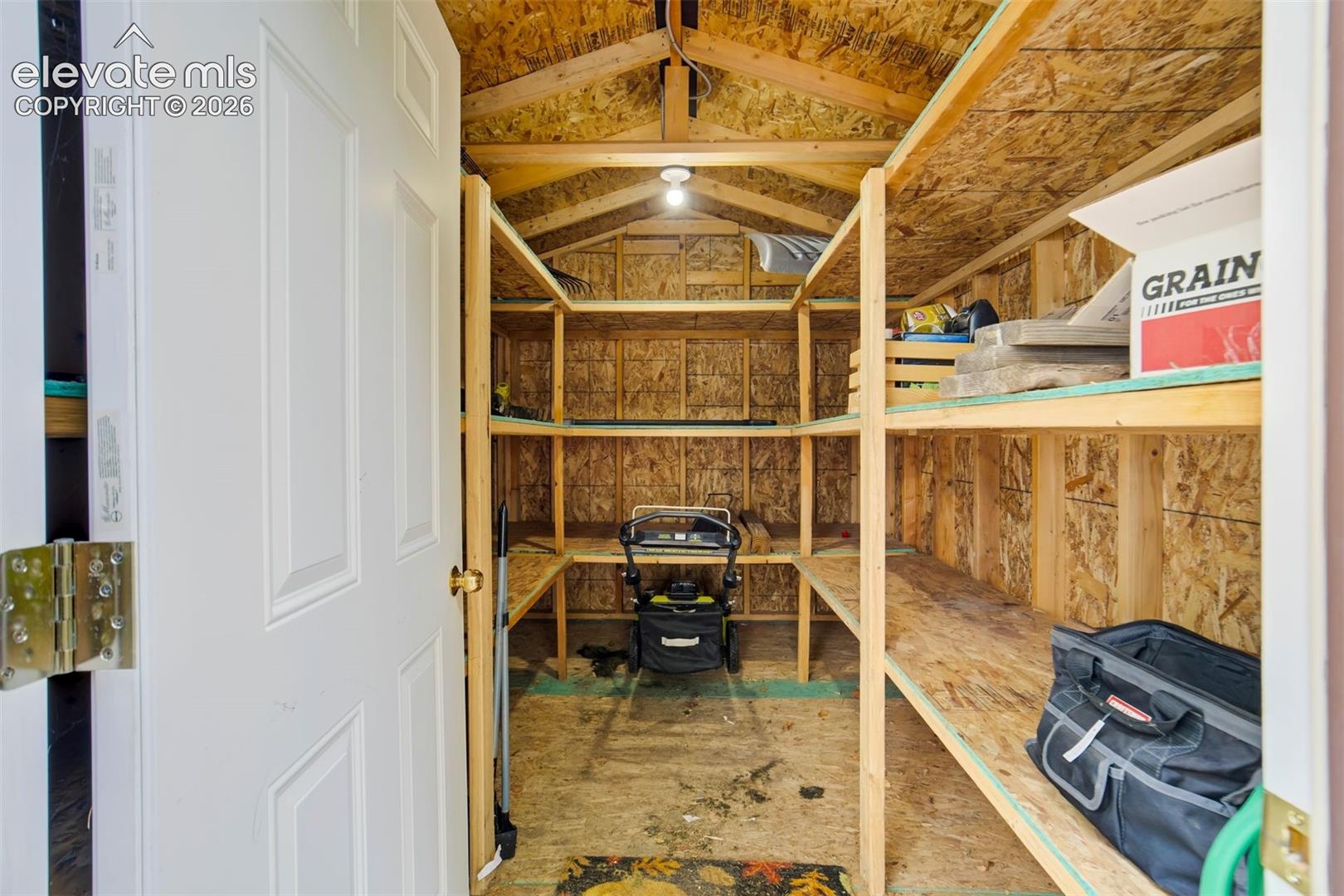 Shed has ample shelving and electricity connected.